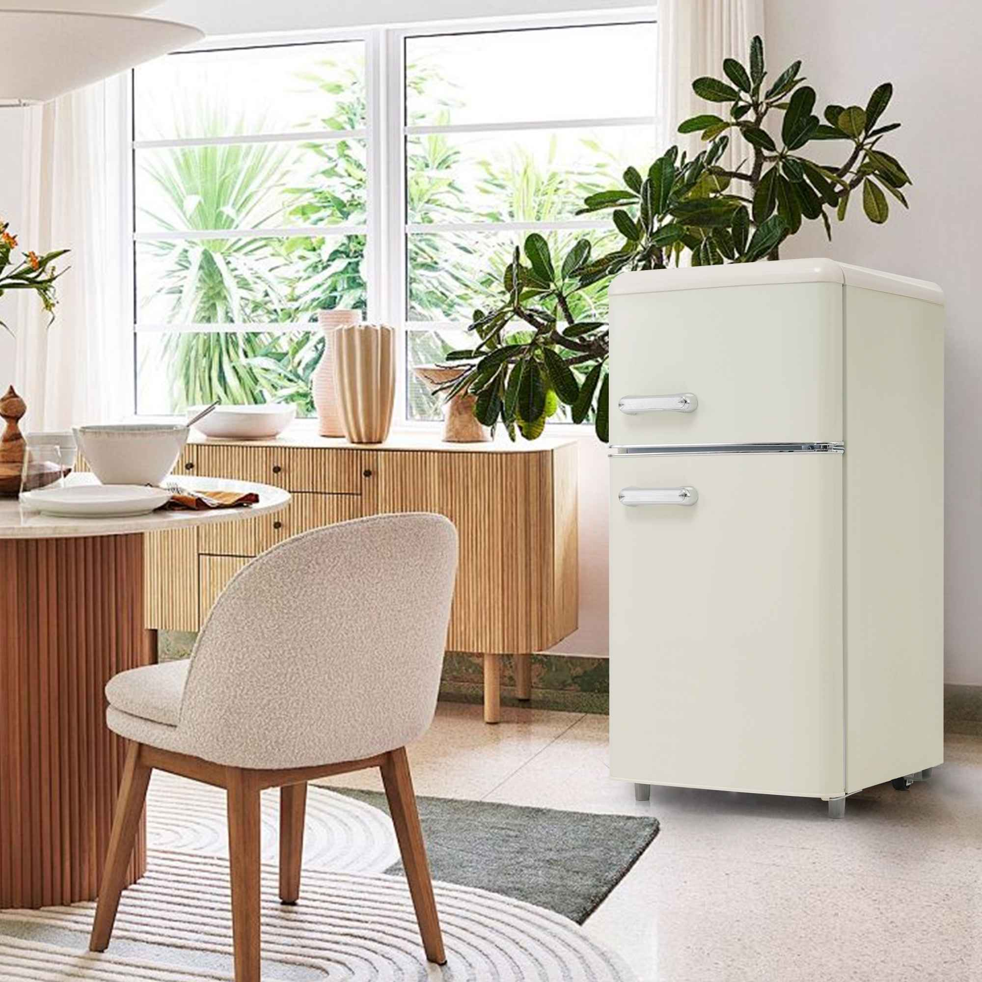 Ein Kühlschrank im Retro-Stil in einer Küche. Es gibt einen Tisch und Stühle vor einem Fenster.