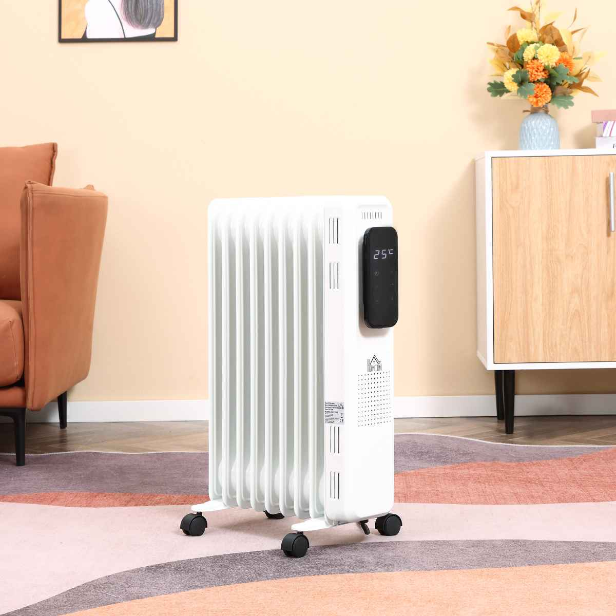 Ein weißer Heizkörper mit digitaler Anzeige von 25°C. Er steht auf einem Teppich. Sofa und Schrank im Hintergrund.