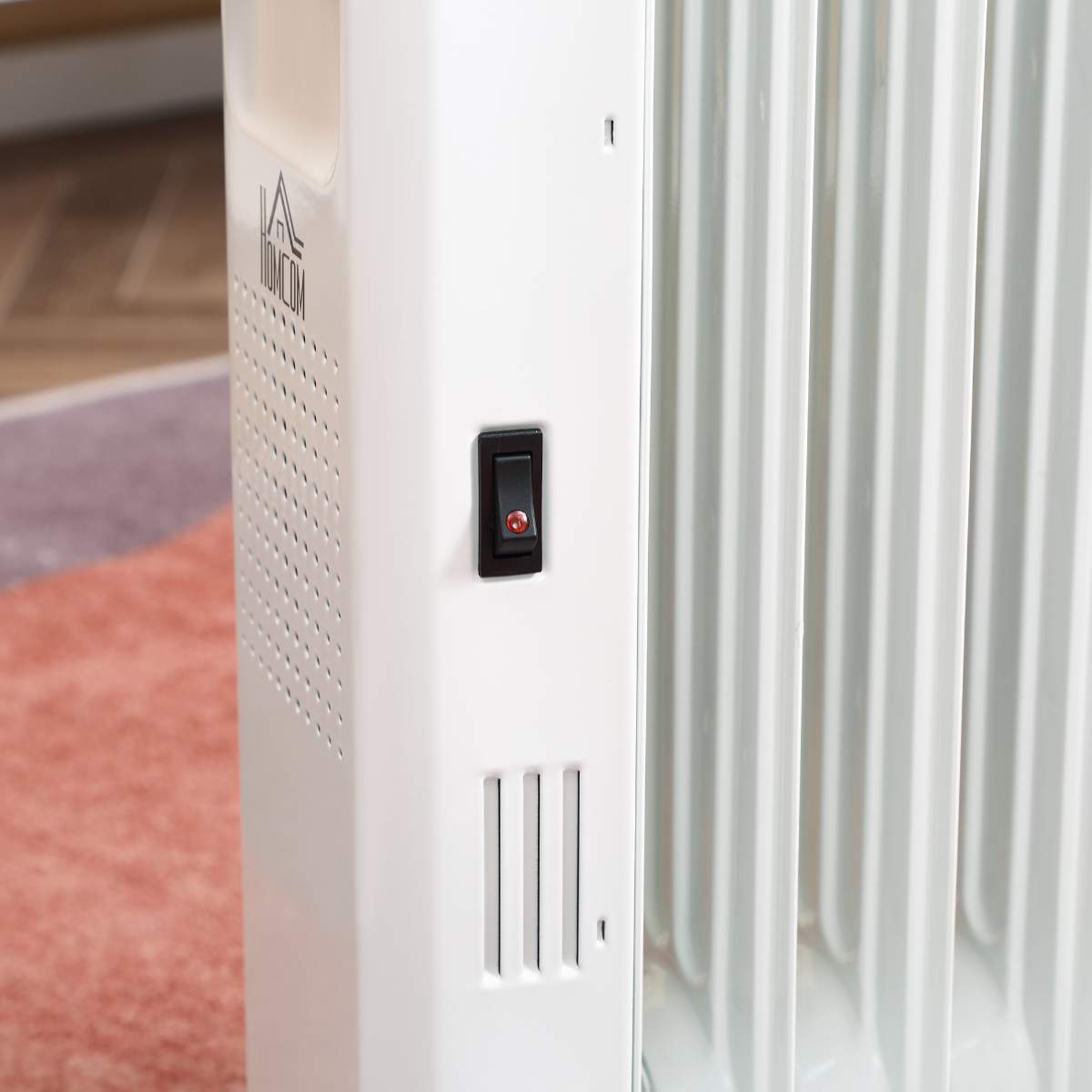 Nahaufnahme eines weißen elektrischen Heizkörpers. Der Schalter ist schwarz und rot, mit roter Kontrollleuchte.