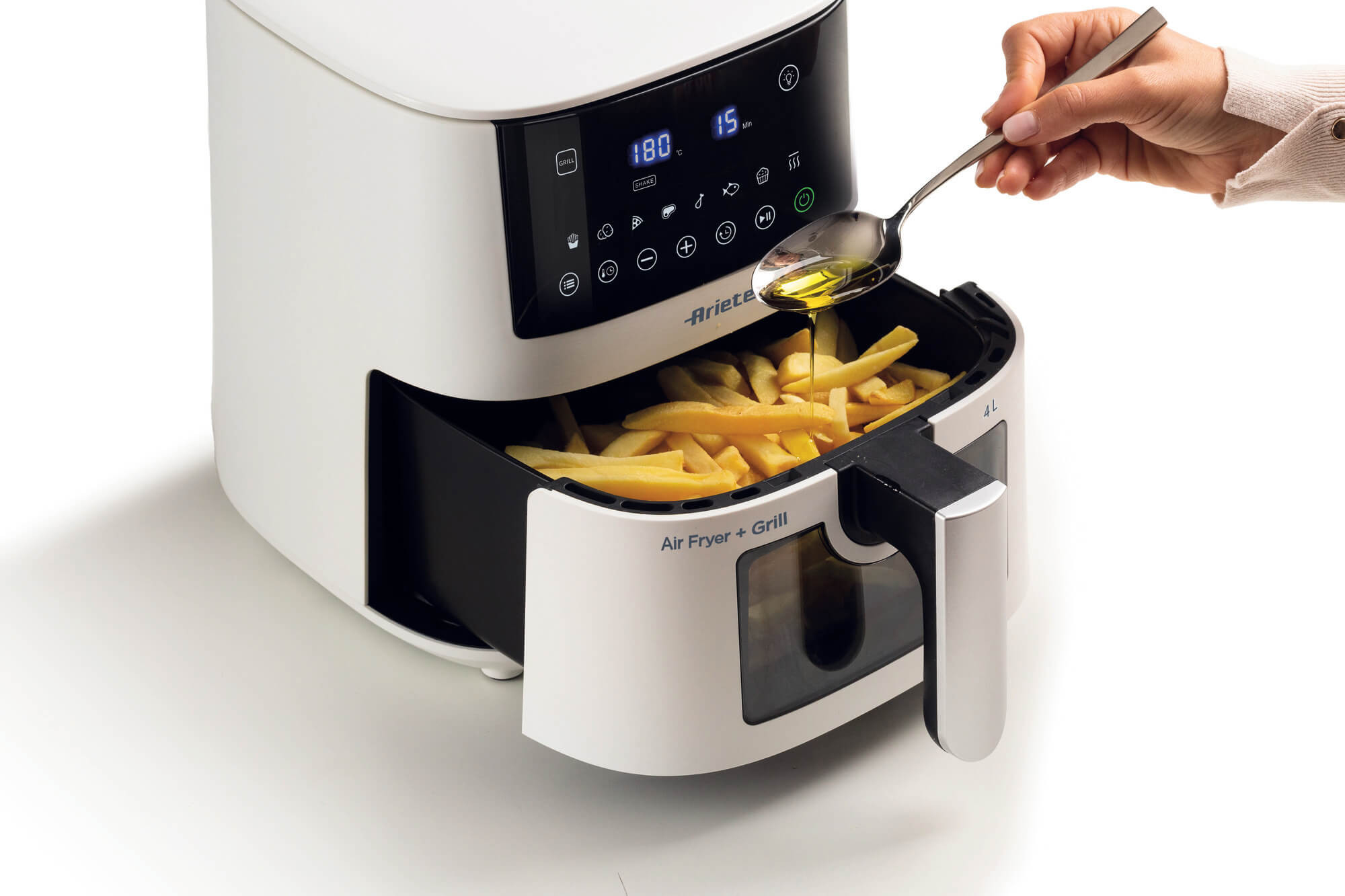 Biało-czarna frytkownica beztłuszczowa z tacą frytek, które są doprawiane olejem za pomocą łyżki.