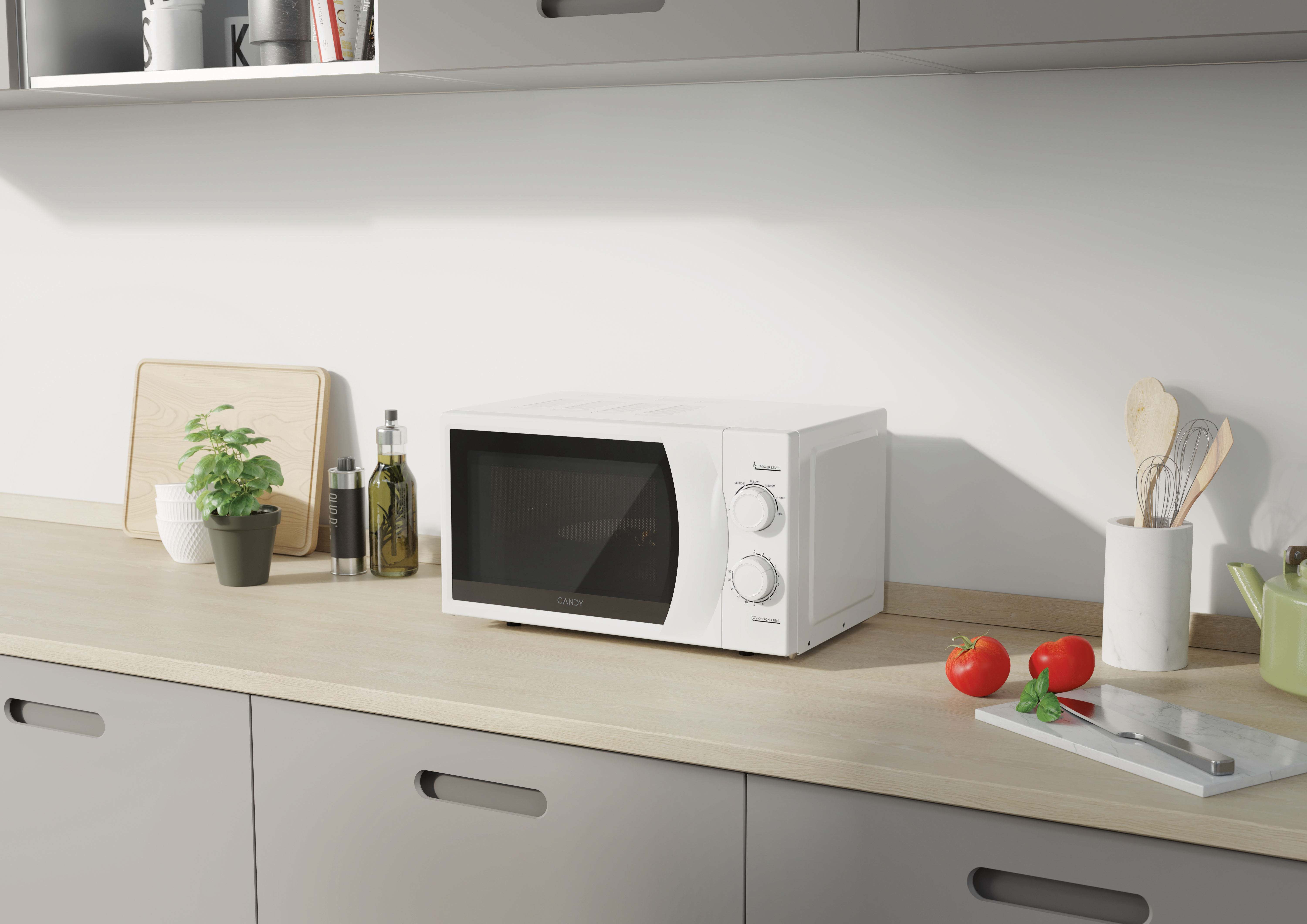 Biała kuchenka mikrofalowa na jasnym blacie. Kuchnia z roślinami, butelkami z olejem i pomidorami.