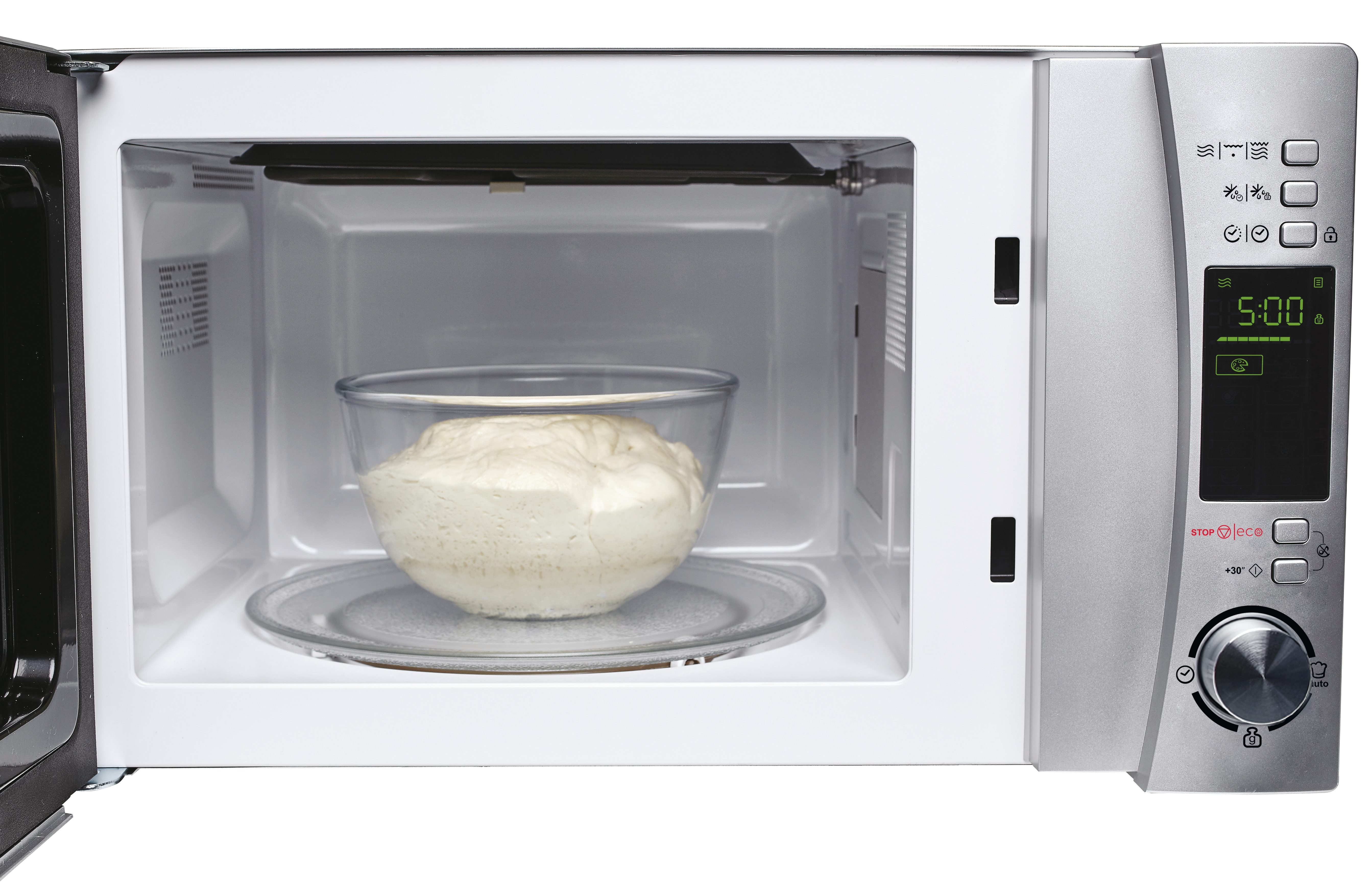 Un microonde con la porta aperta. Una ciotola di impasto all'interno. Interno bianco.