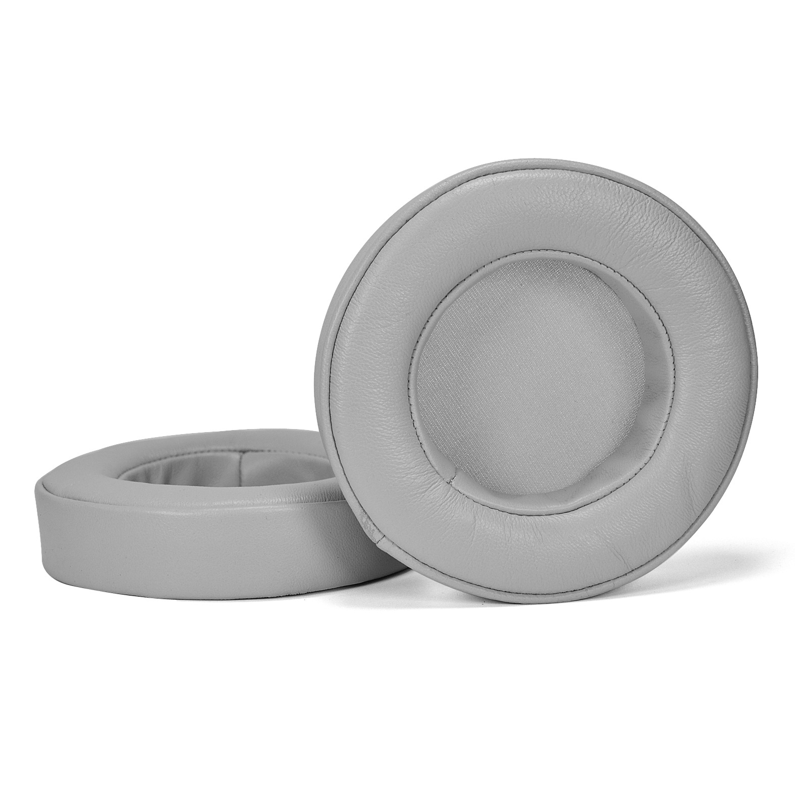 Dwie szare poduszki na uszy na białej powierzchni, o okrągłym kształcie.