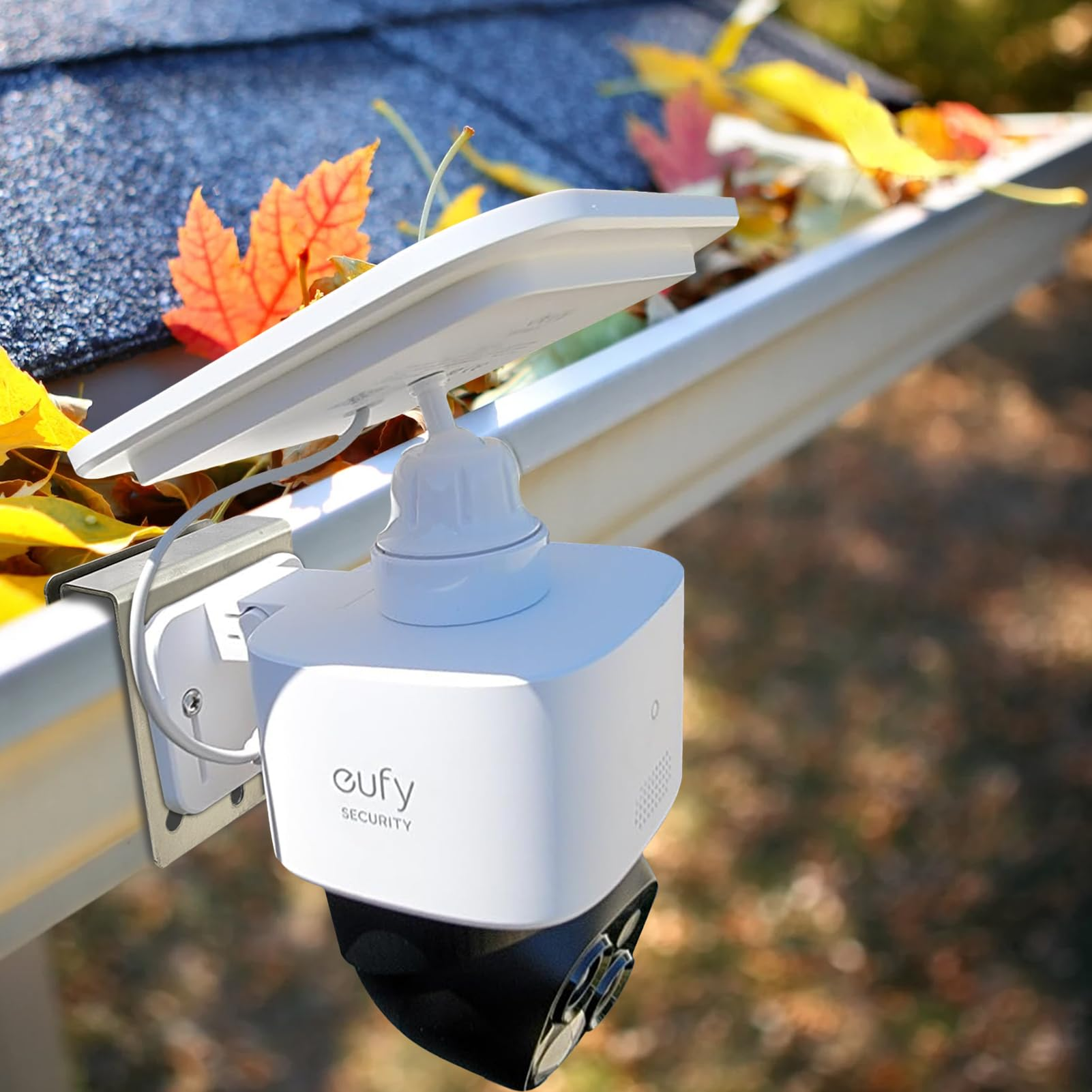 Eine weiße Solarkamera, montiert an einer mit Herbstblättern gefüllten Dachrinne.