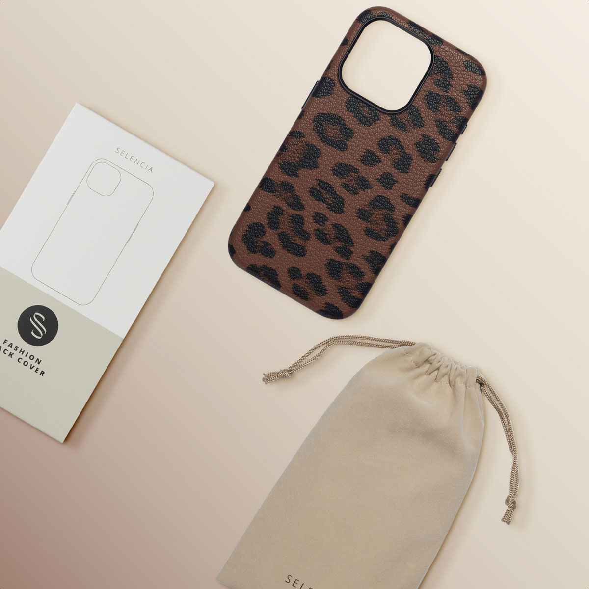 Een telefoonhoesje, een tas en een witte doos met luipaardprint op een beige oppervlak.
