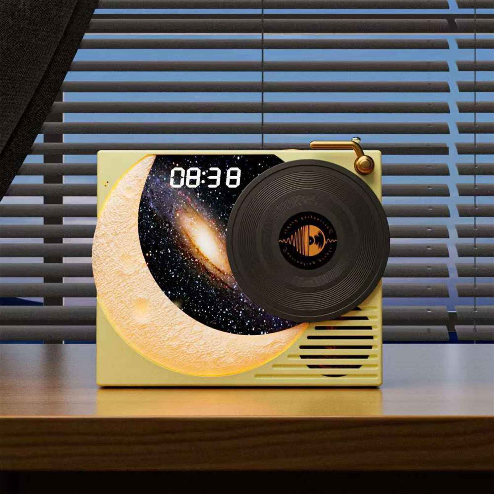 Ein Lautsprecher in Form eines Plattenspielers mit Mond- und Galaxie-Anzeige, die 08:38 zeigt. Im Hintergrund ein Fenster mit Jalousien.