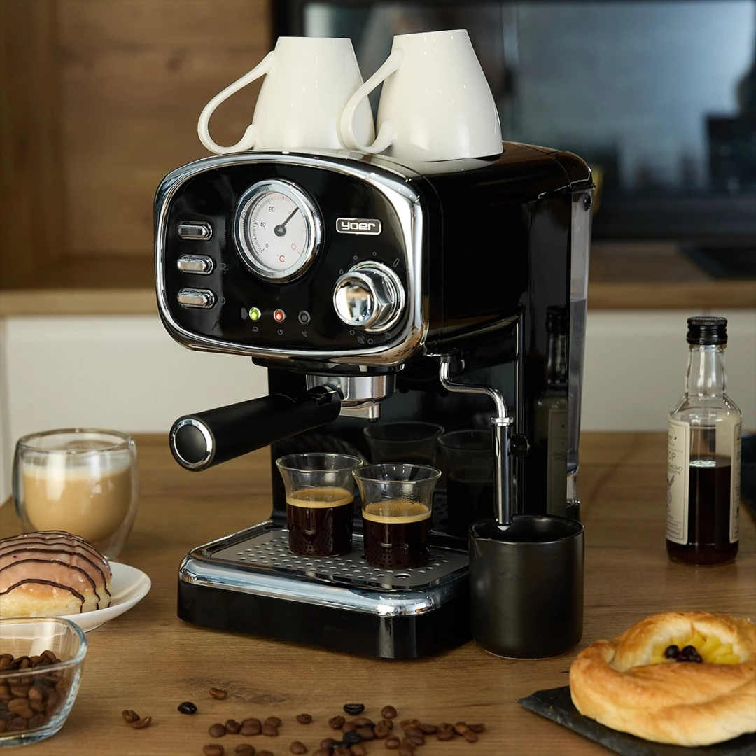 Czarny ekspres do kawy z filiżankami, dwoma espresso i ciastkami na drewnianym blacie.