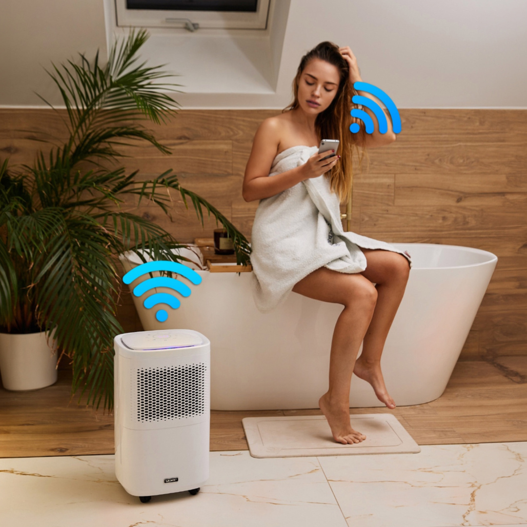 Kobieta w łazience z ręcznikiem, używa telefonu. Osuszacz i symbol wifi w scenie.