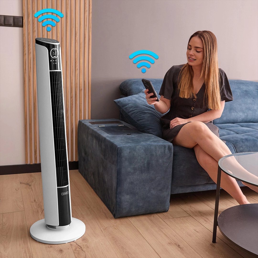 Kobieta w salonie używa smartfona. Wentylator wieżowy i symbol wifi w scenie.