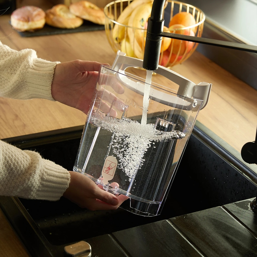 Osoba napełnia zbiornik na wodę wodą z kranu.