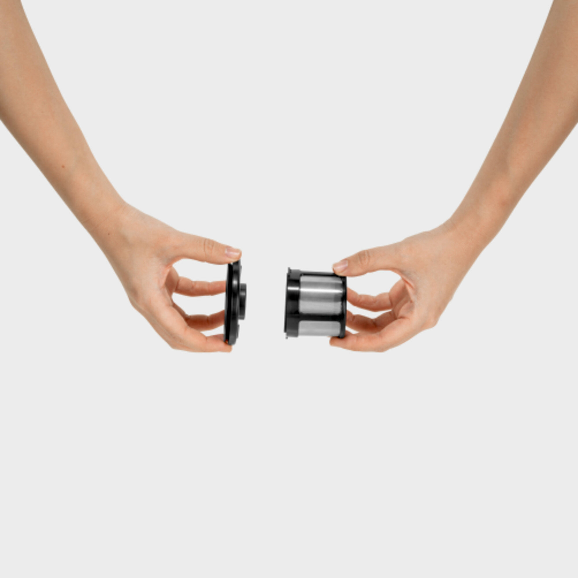 Dwie dłonie trzymające czarne i srebrne cylindryczne przedmioty, gotowe do połączenia. Białe tło.