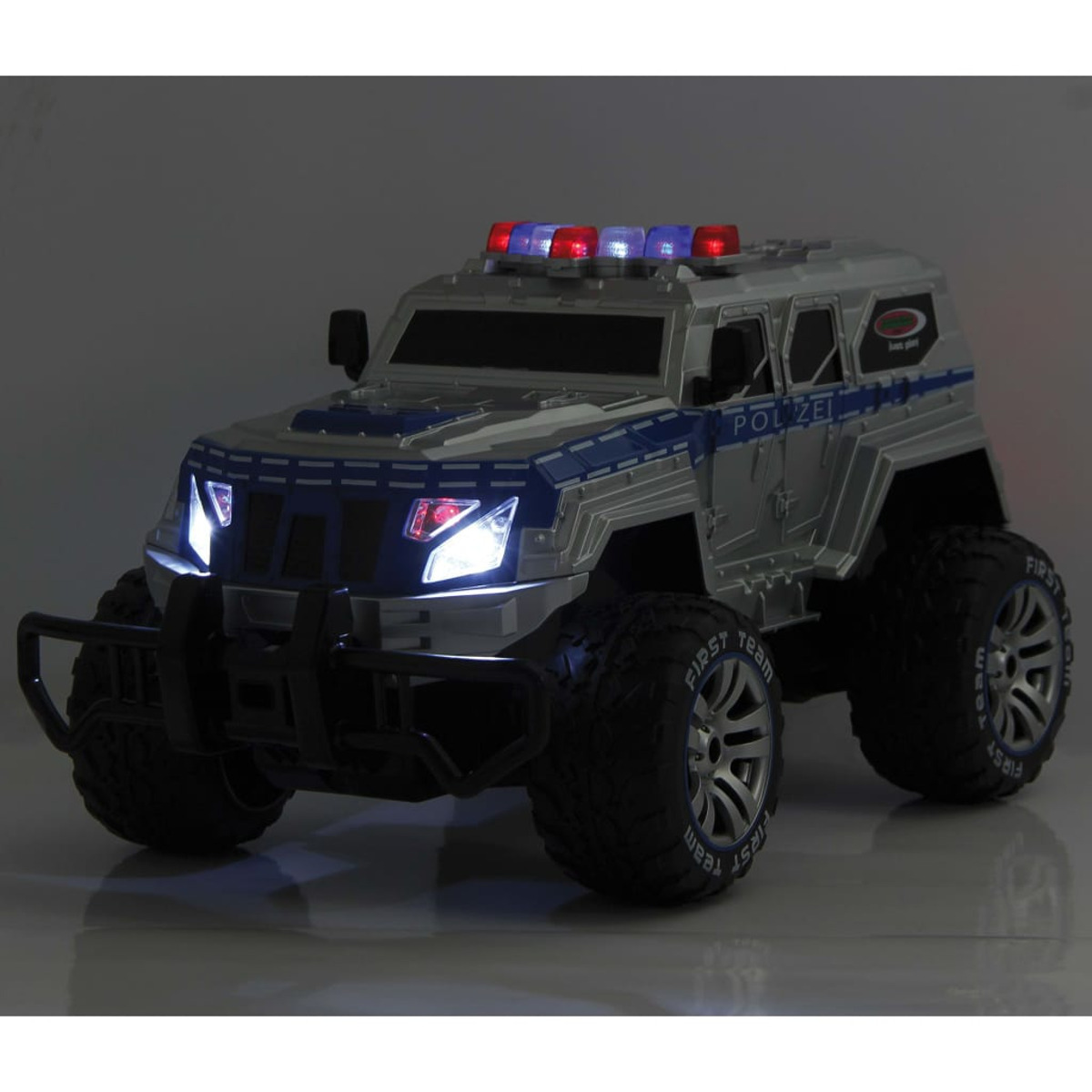 Ein silberner Polizeiwagen mit eingeschalteten Lichtern, mit großen Reifen und dem Wort 'POLIZEI' an der Seite, in dunkler Umgebung.