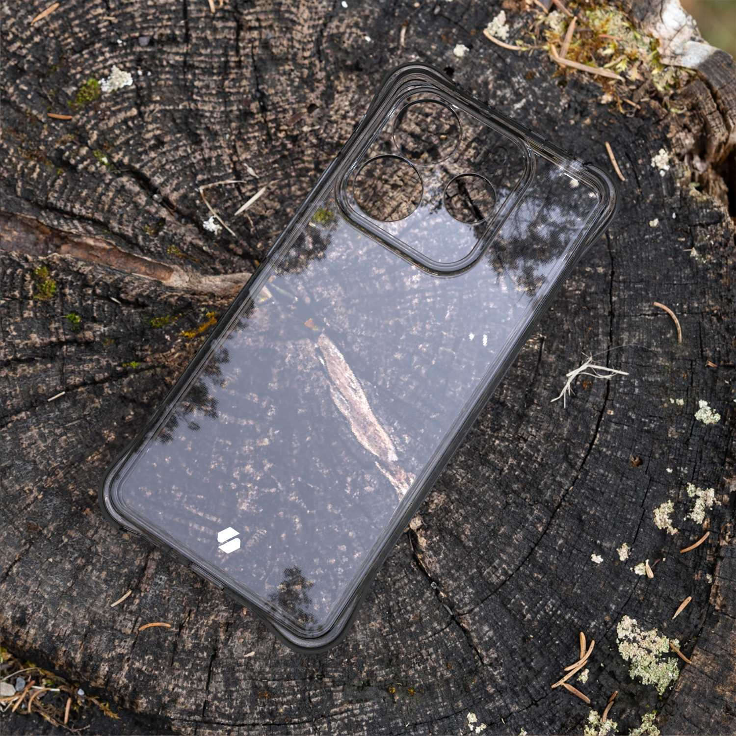 Przezroczyste etui na telefon na pniu drzewa. Widoczna faktura.