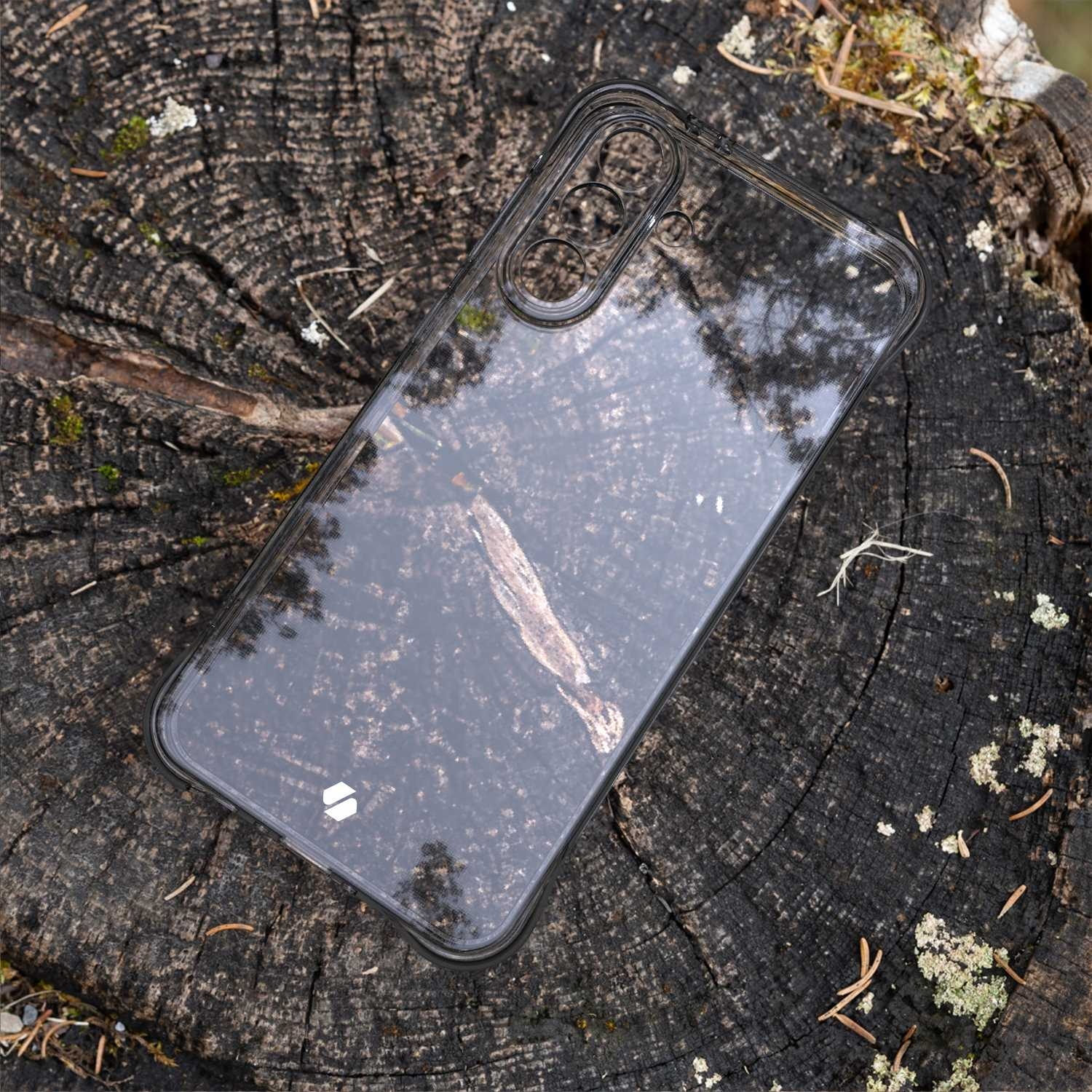 Przezroczyste etui na pniu drzewa. Etui odbija korę i niebo.