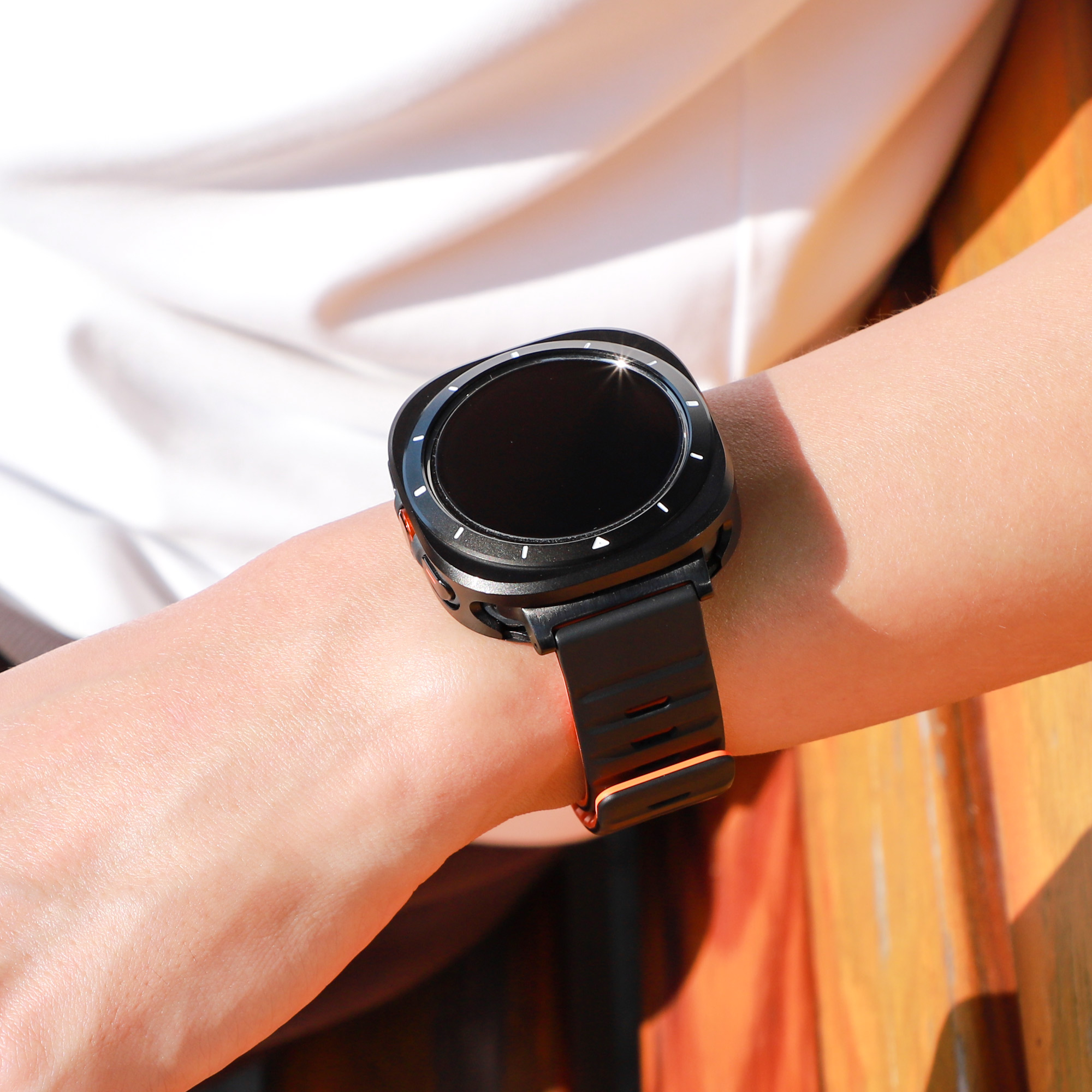 Eine Person, die eine schwarze Smartwatch mit schwarzem Armband trägt. Die Uhr ist an ihrem Handgelenk.