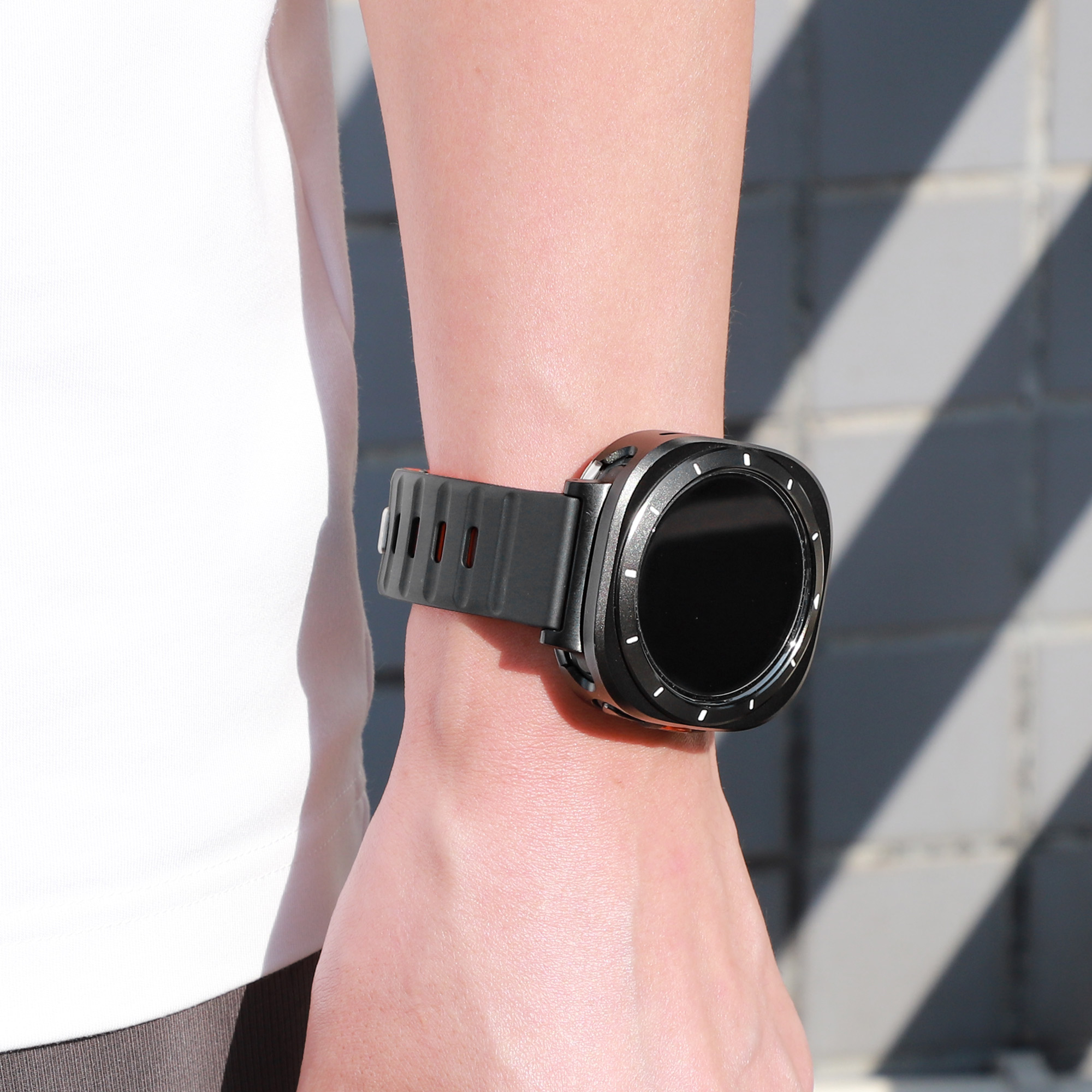 Eine Person, die eine schwarze Smartwatch an ihrem Handgelenk trägt. Die Uhr hat ein schwarzes Armband und ein rundes Zifferblatt.