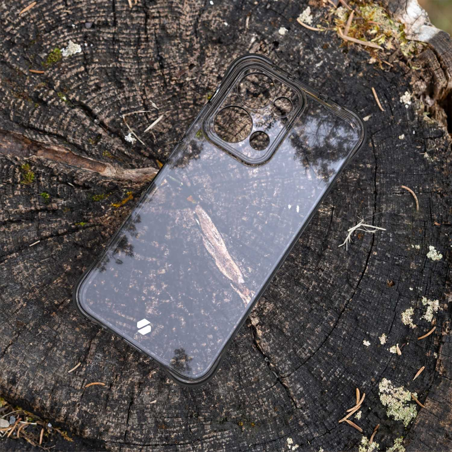 Przezroczyste etui na telefon na drewnianej powierzchni. Etui jest przezroczyste, ukazując ciemne, wzorzyste tło.