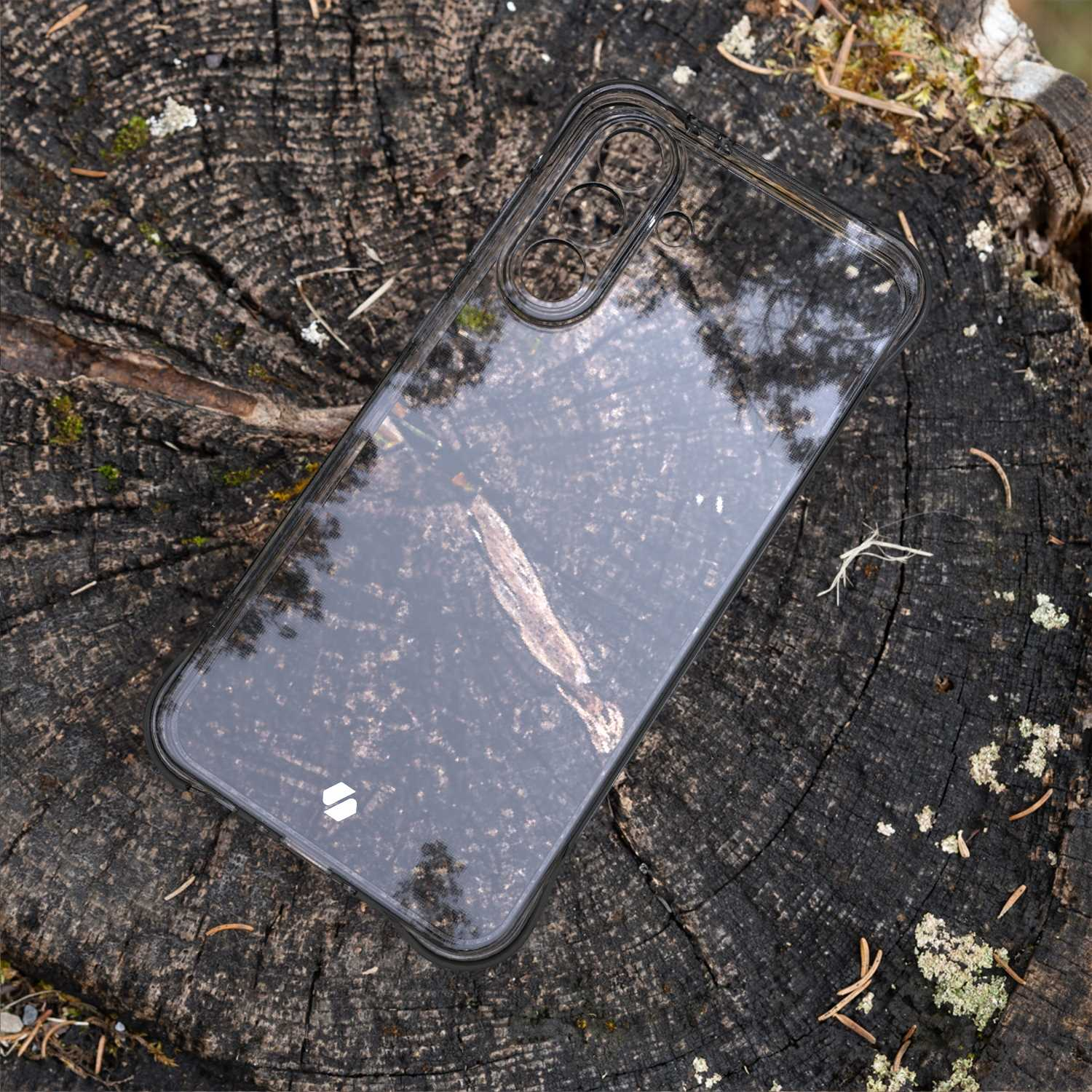 Przezroczyste etui na pniu drzewa. Etui jest pod kątem i pokazuje odbicie.