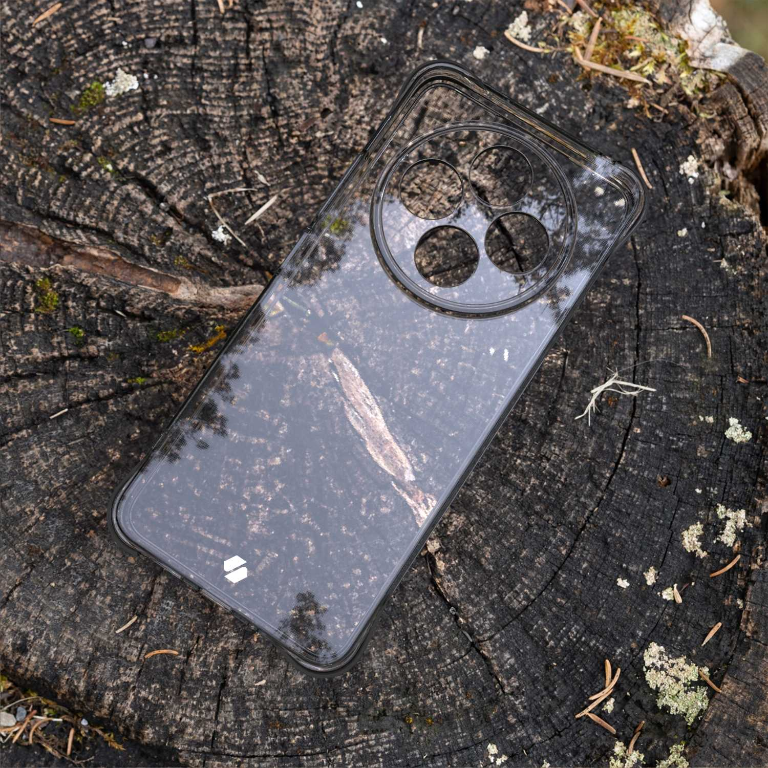 Przezroczyste etui na telefon na drewnianym pniu. Telefon pokazuje ciemny wzór.