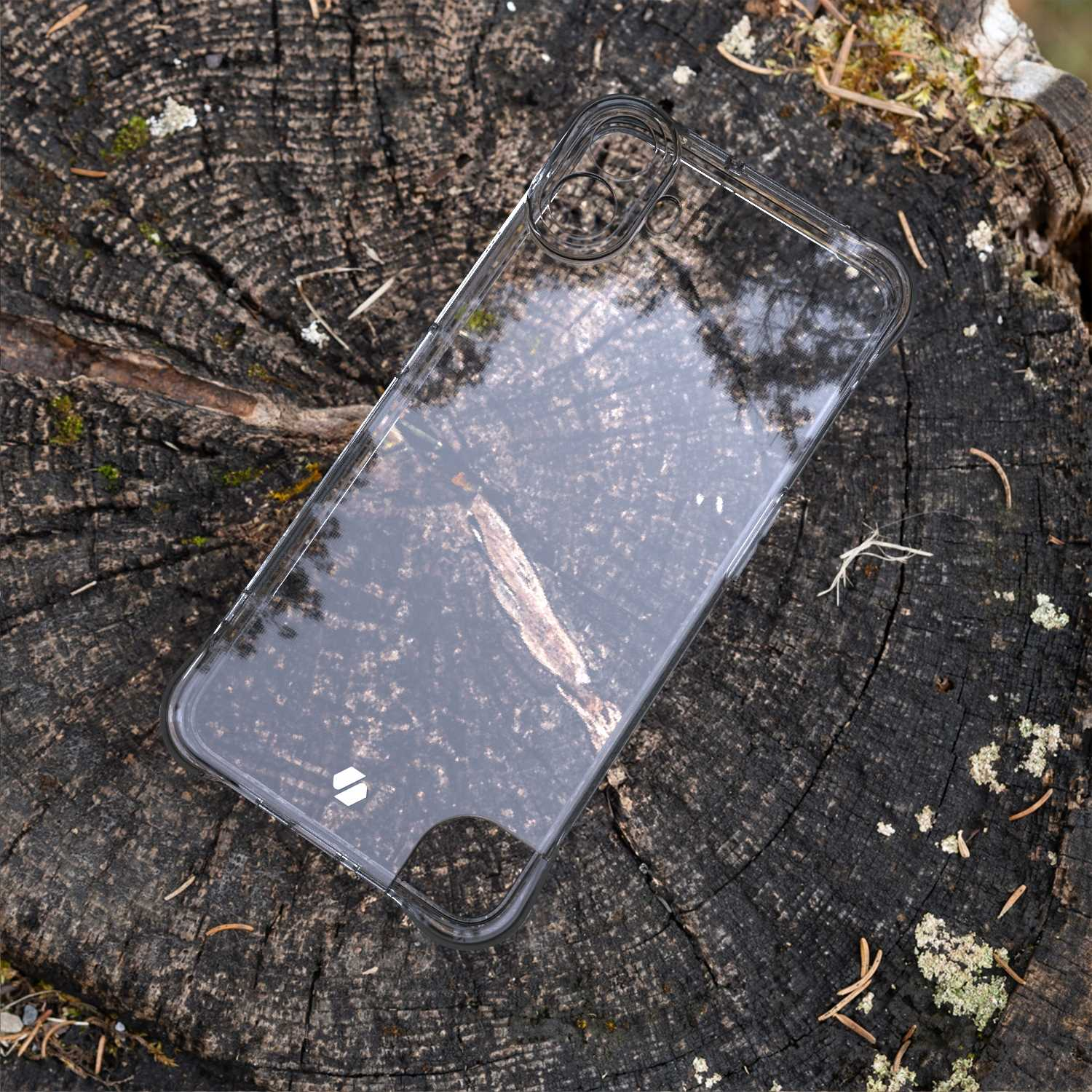 Przezroczyste etui na telefon na fakturowanym pniu, z odbiciem nieba.