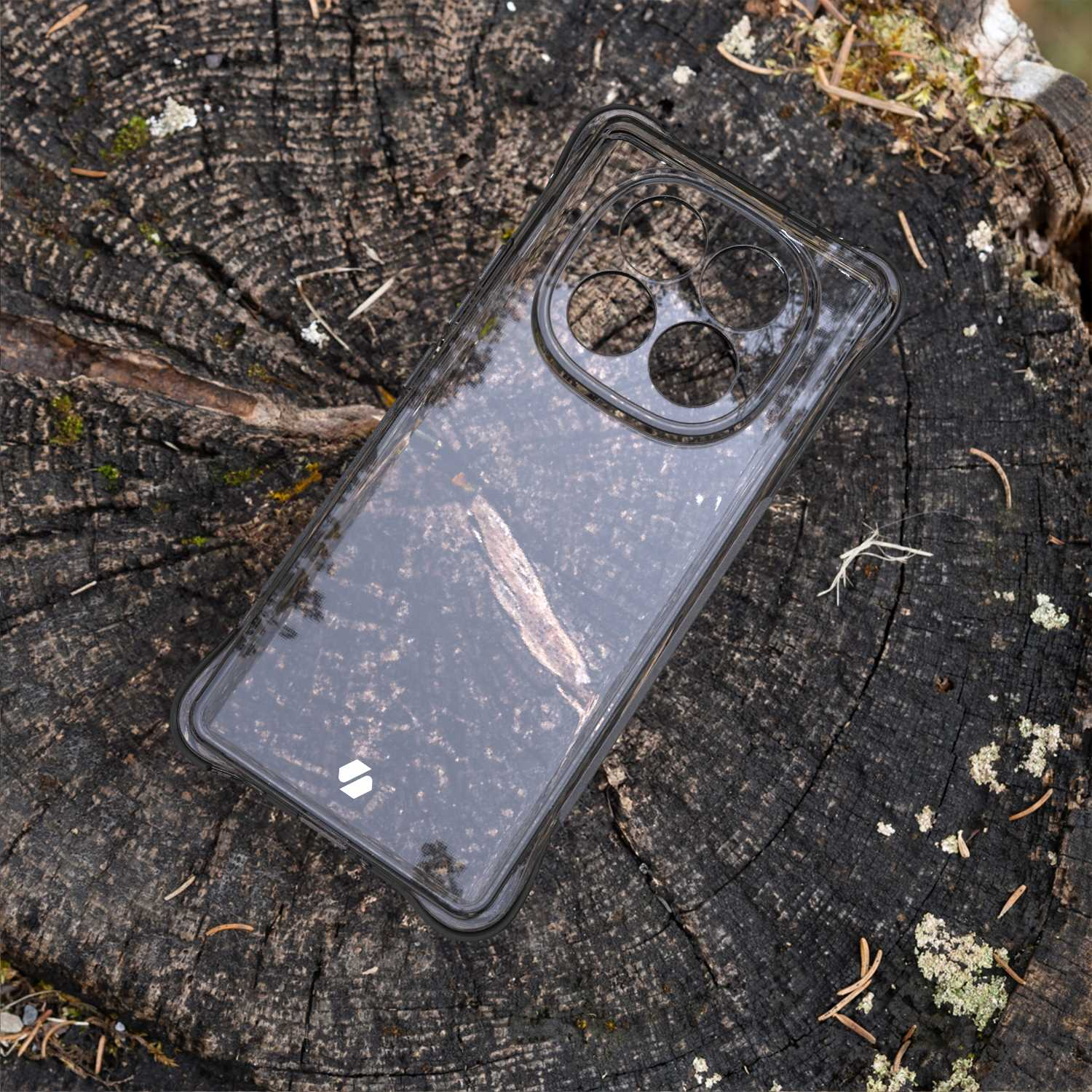 Przezroczyste etui na telefon na pniu drzewa. Etui jest na ciemnym telefonie.