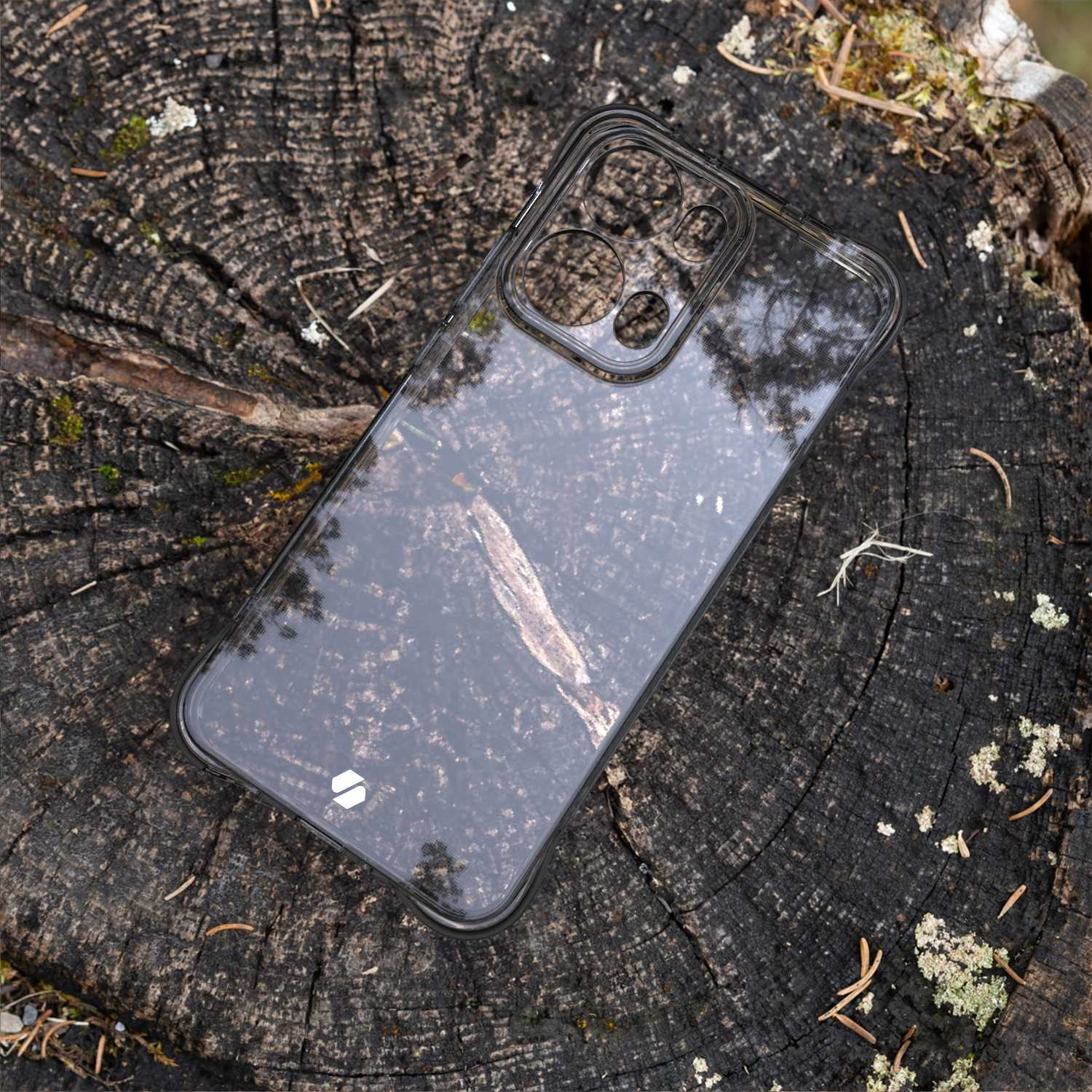 Przezroczyste etui na telefon na pniu drzewa. Etui jest na ciemnym telefonie.