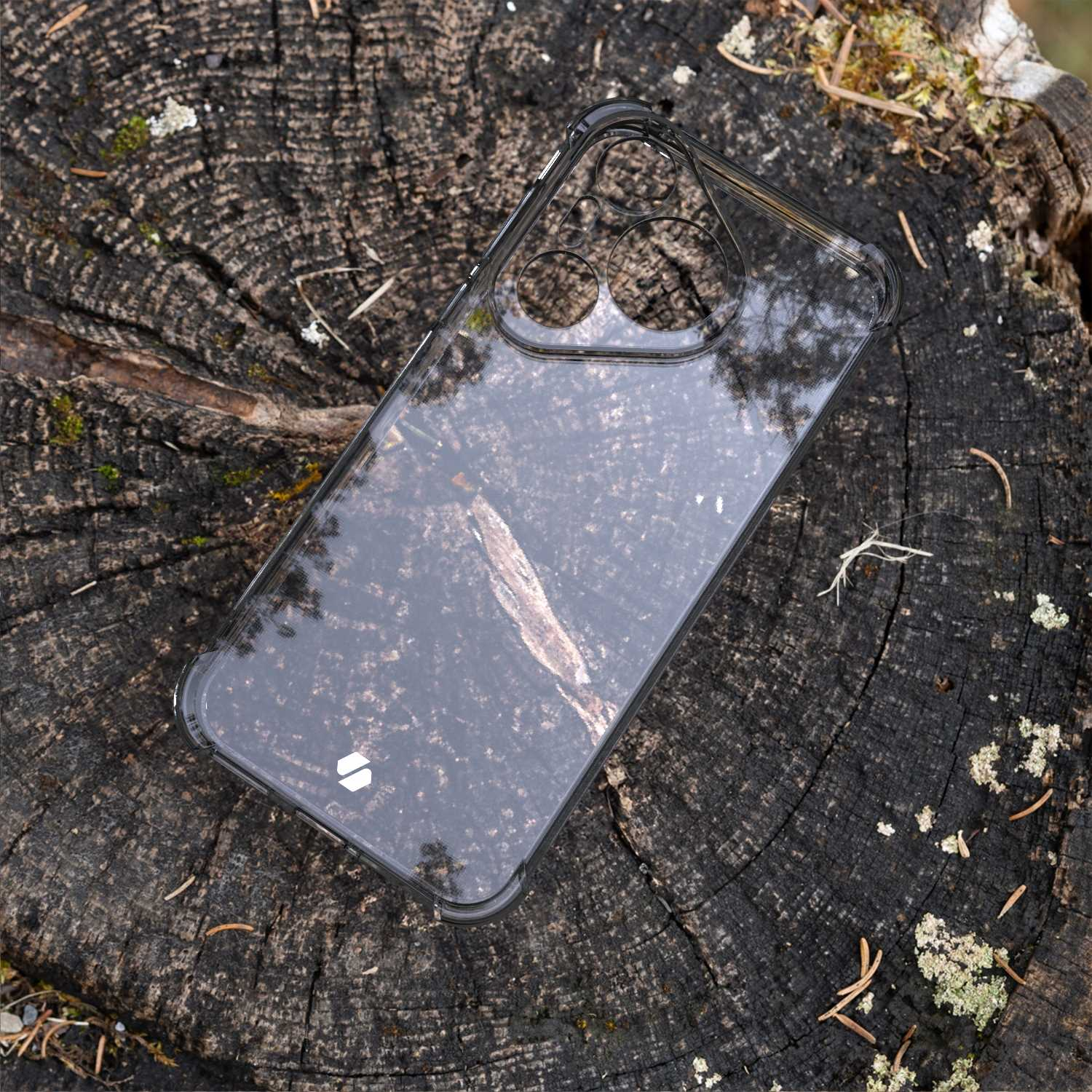 Przezroczyste etui na telefon na pniu drzewa. Etui jest przezroczyste, pokazujące powierzchnię drewna pod spodem.
