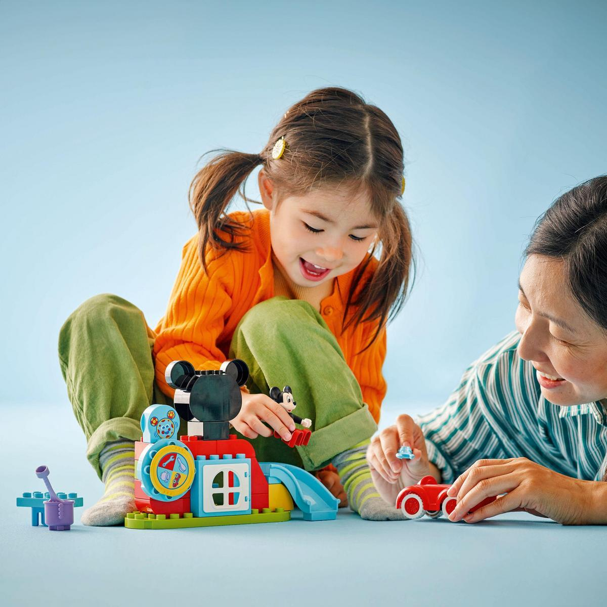 Dziecko i dorosły bawią się zestawem Lego Duplo z Myszką Miki, pociągiem i zjeżdżalnią.