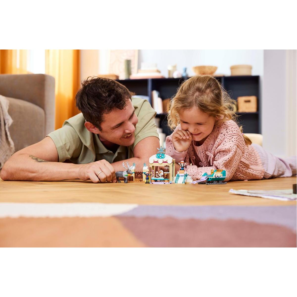 Un padre y su hija jugando con un set de Lego en un suelo de madera.