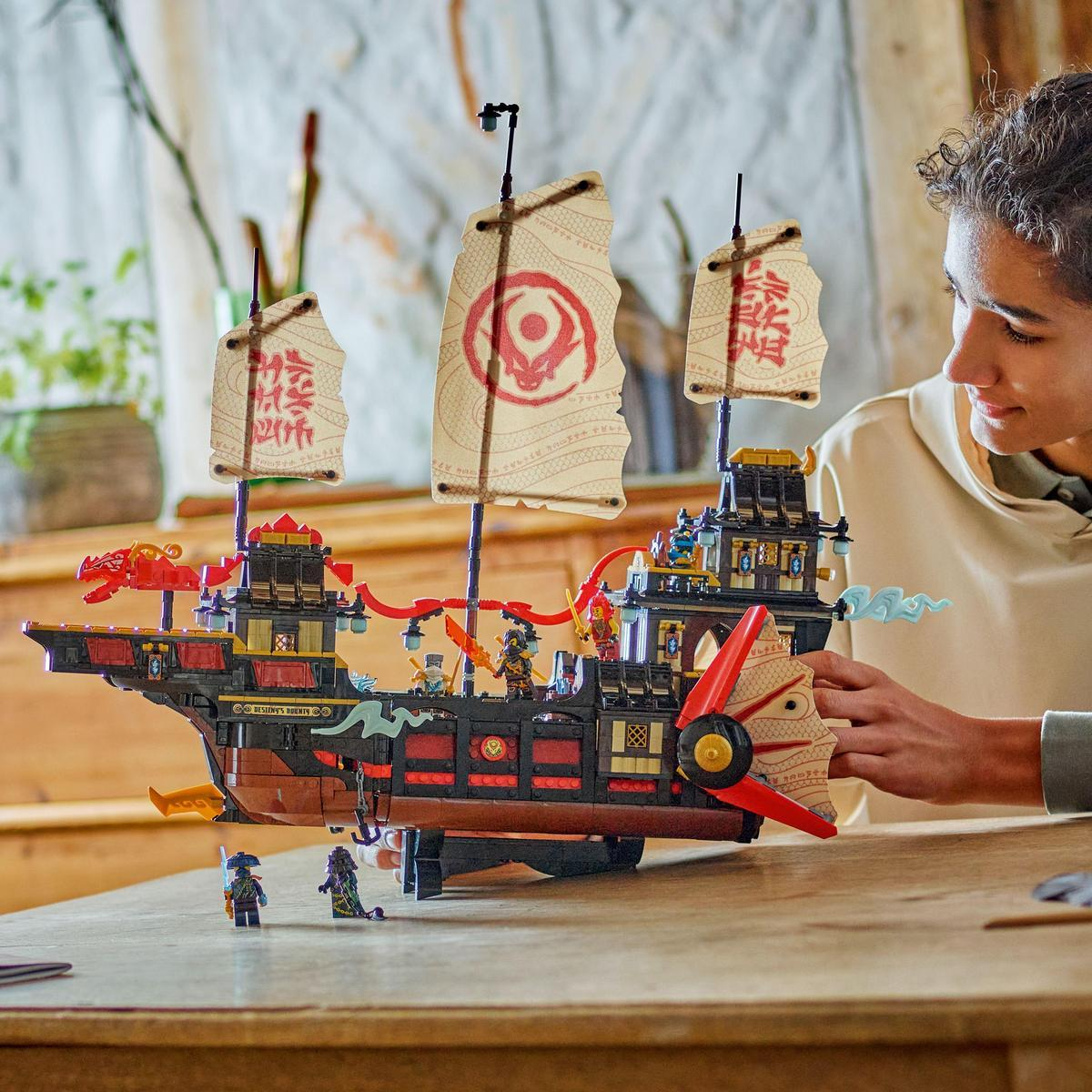 Nastolatek bawi się statkiem Lego. Statek ma duże żagle z chińskimi znakami.