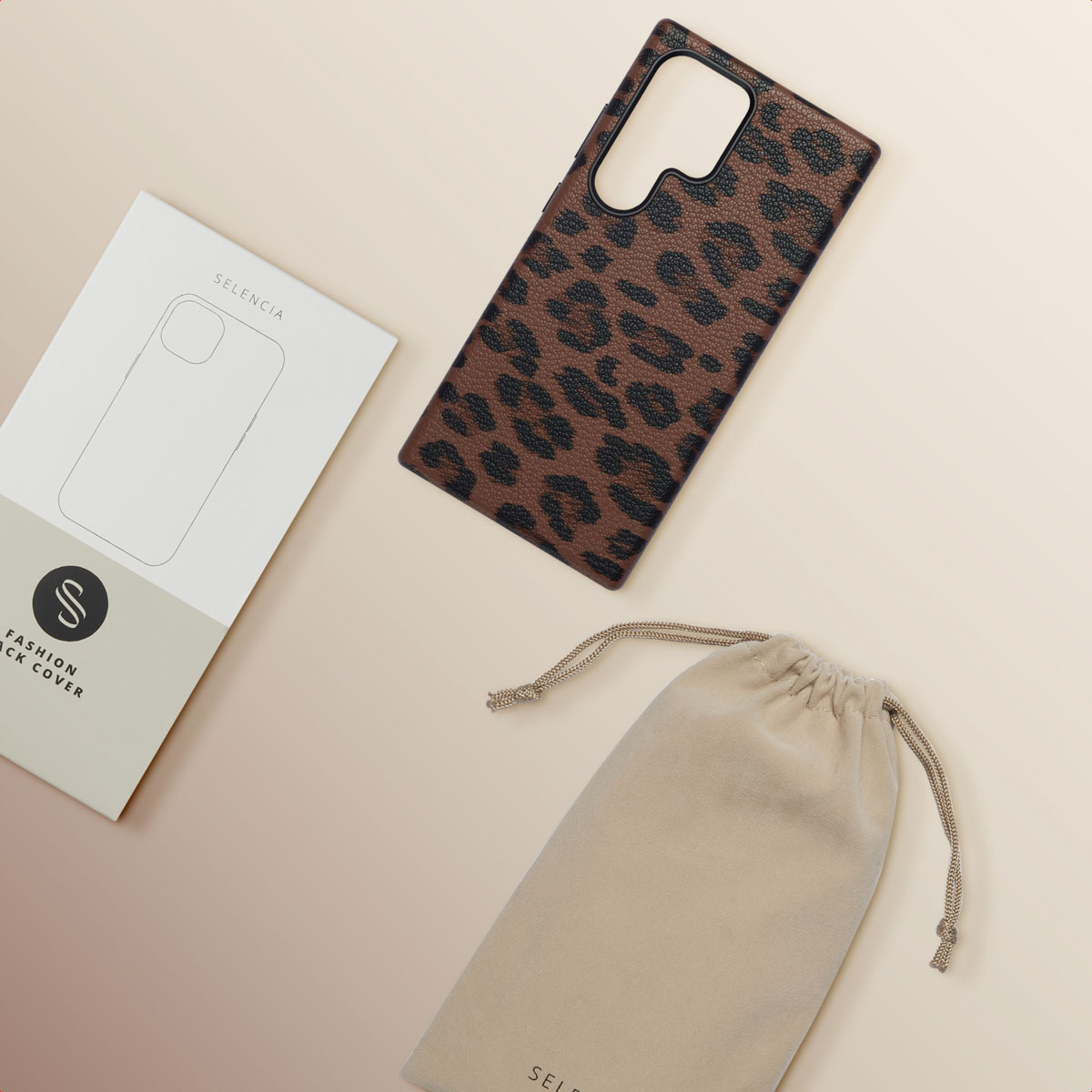 Een bruin telefoonhoesje met luipaardprint naast een doos en een zakje, alles op een beige oppervlak, platliggend.