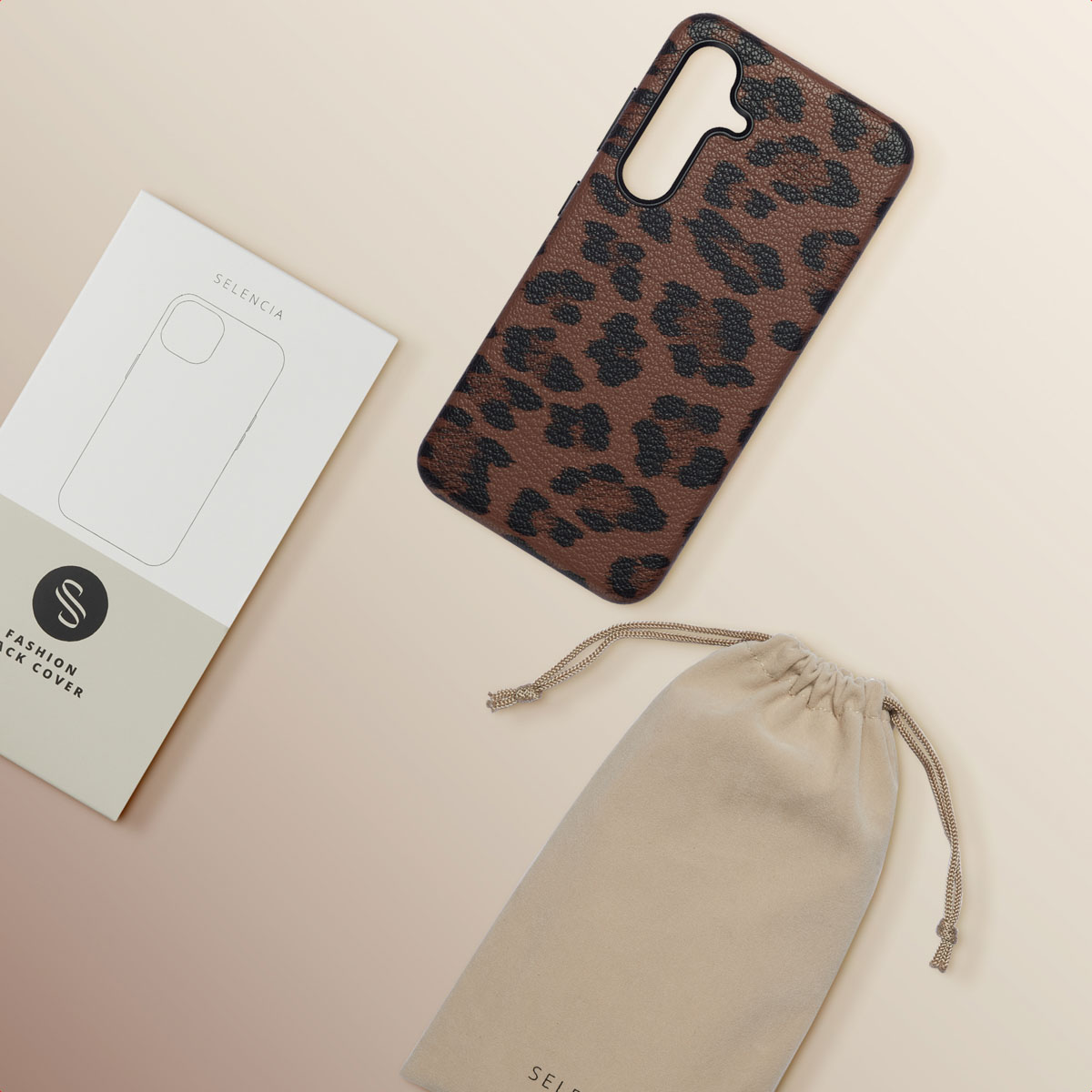 Een telefoonhoesje, een tas en een verpakking liggen op een oppervlak. Het telefoonhoesje heeft een luipaardprint.