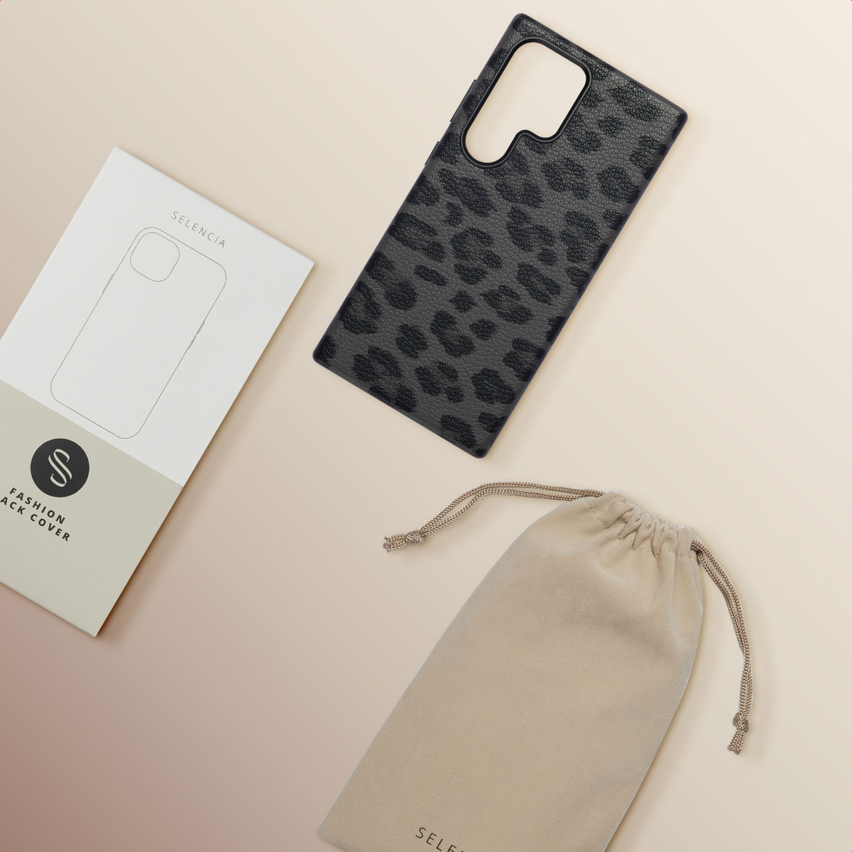 Een telefoonhoesje met zwarte luipaardprint, een witte doos en een beige zakje met trekkoord, op een lichtbeige achtergrond.