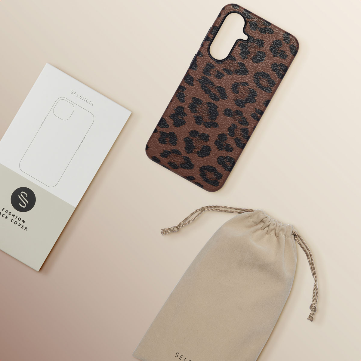 Een telefoonhoesje met bruine luipaardprint, een witte doos en een beige zakje met trekkoord, op een lichtbeige achtergrond.