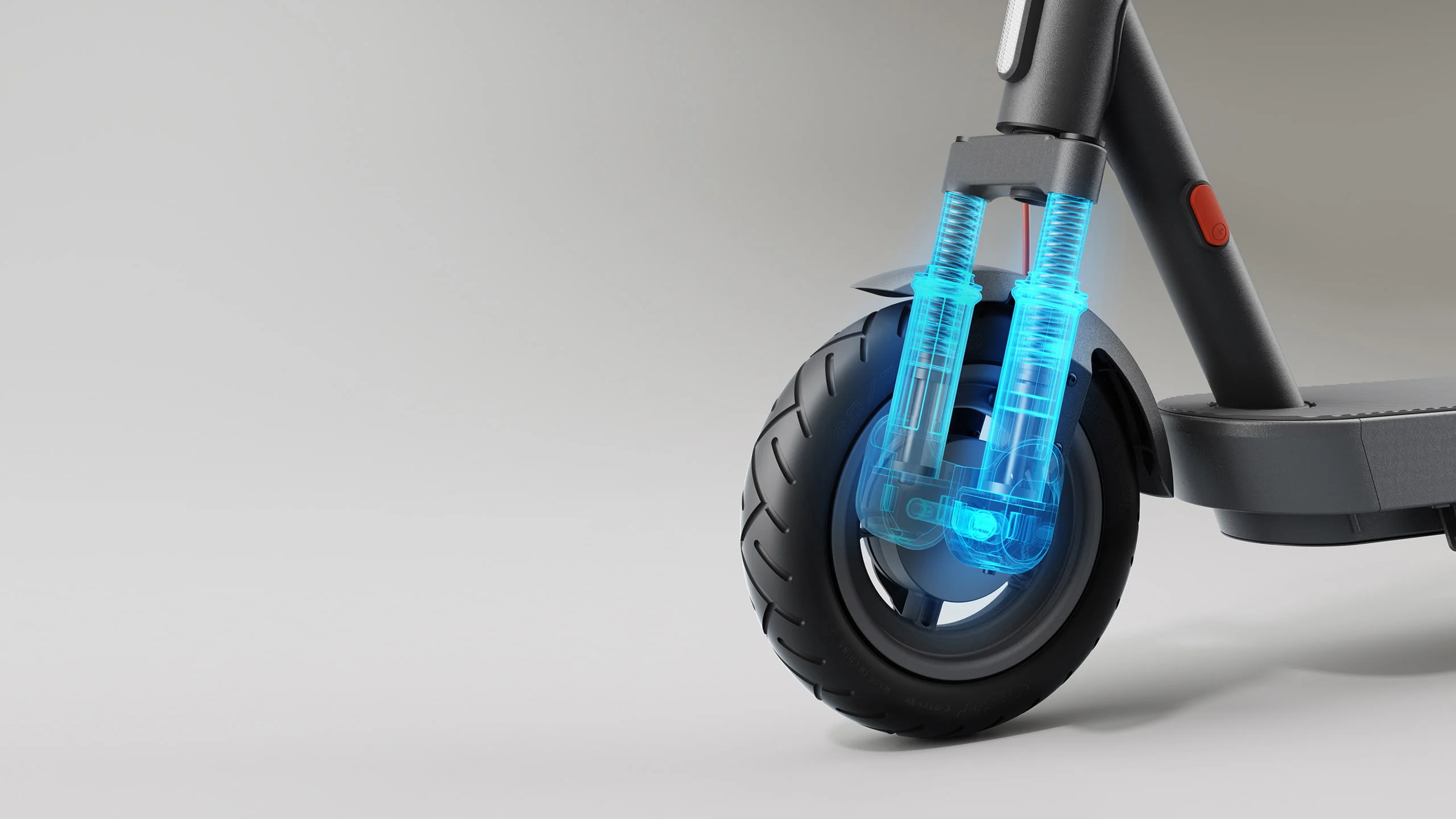 Ruota anteriore dello scooter elettrico con dettagli blu brillanti, su superficie grigio chiaro, sospensione visibile.