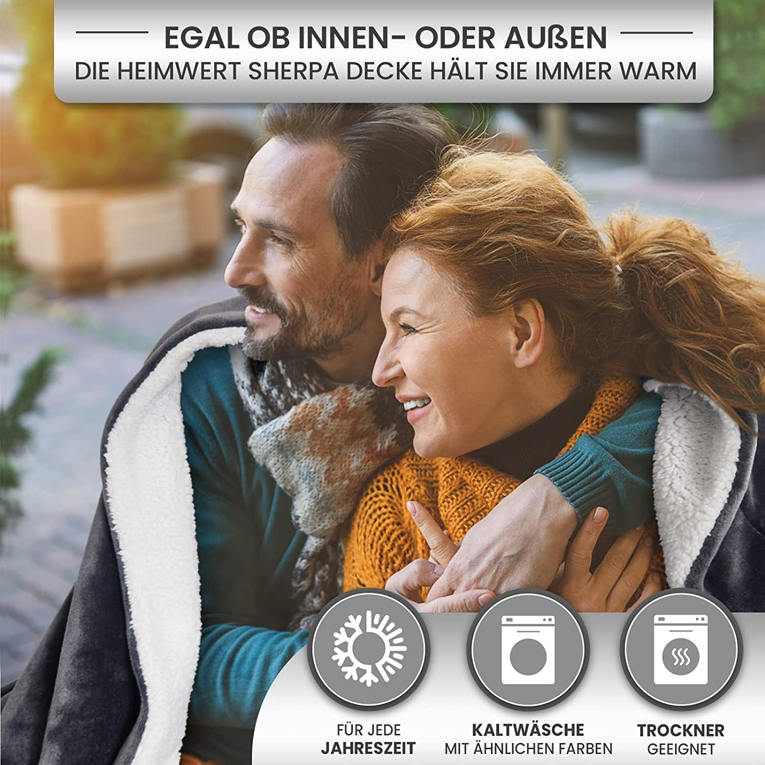 Ein Paar umarmt sich in einer Decke. Der Mann lächelt, die Frau schaut weg. Text: 'Hält Sie warm.'