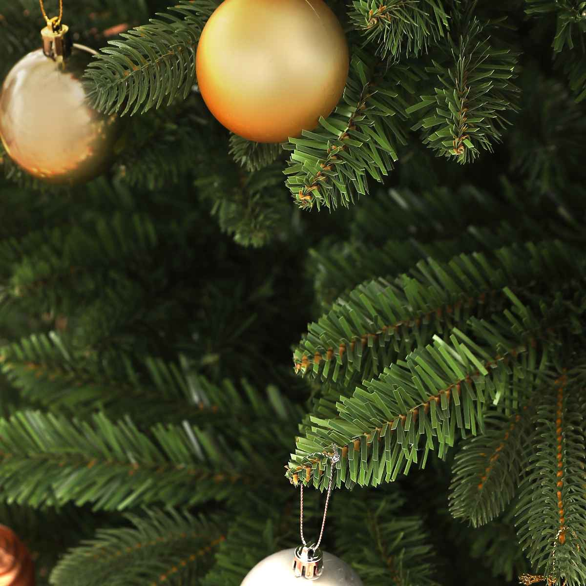 Nahaufnahme von Christbaumschmuck, goldene und silberne Kugeln, auf grünen Nadeln.