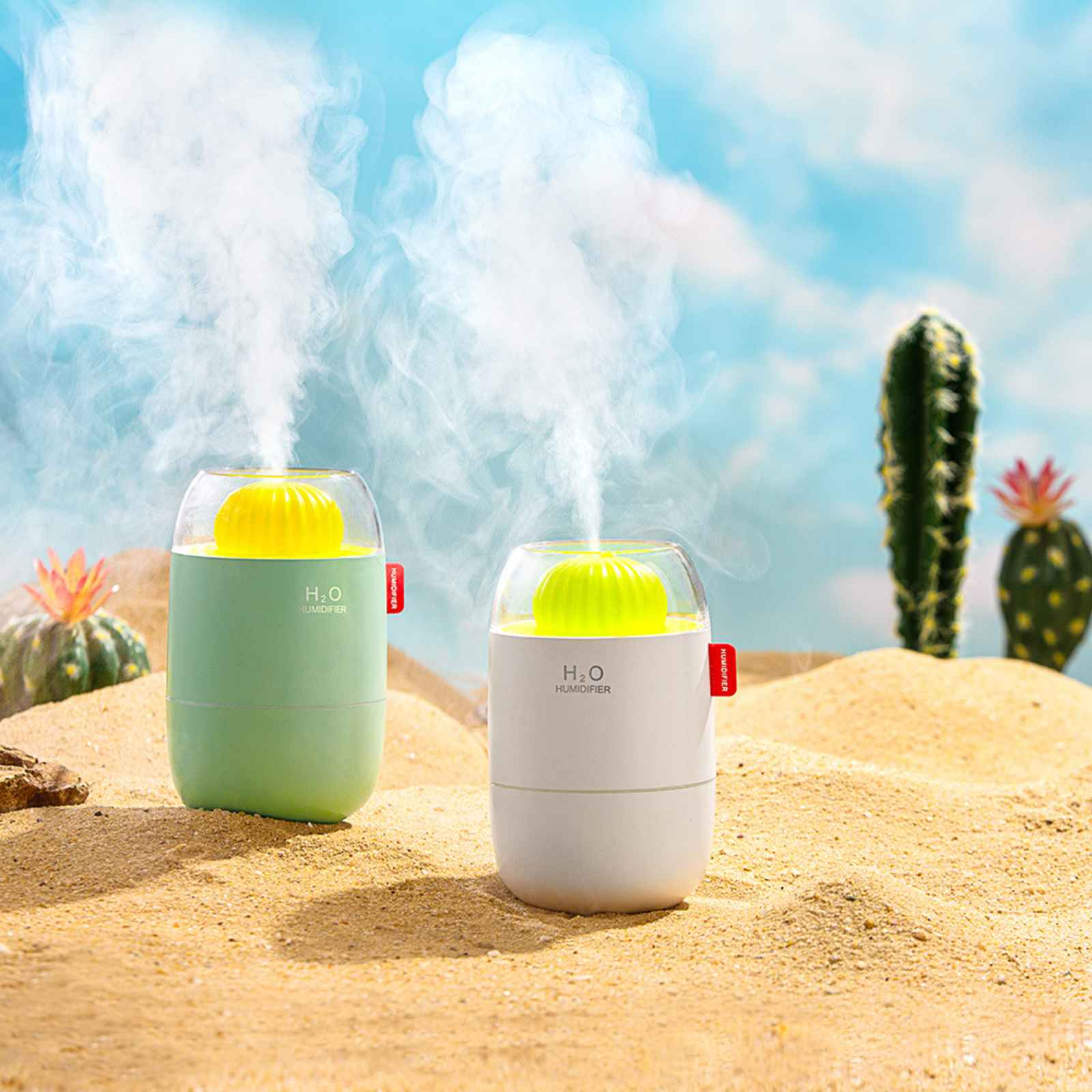 Zwei Luftbefeuchter auf Sand, Dampf steigt auf. Kakteen und blauer Himmel im Hintergrund.