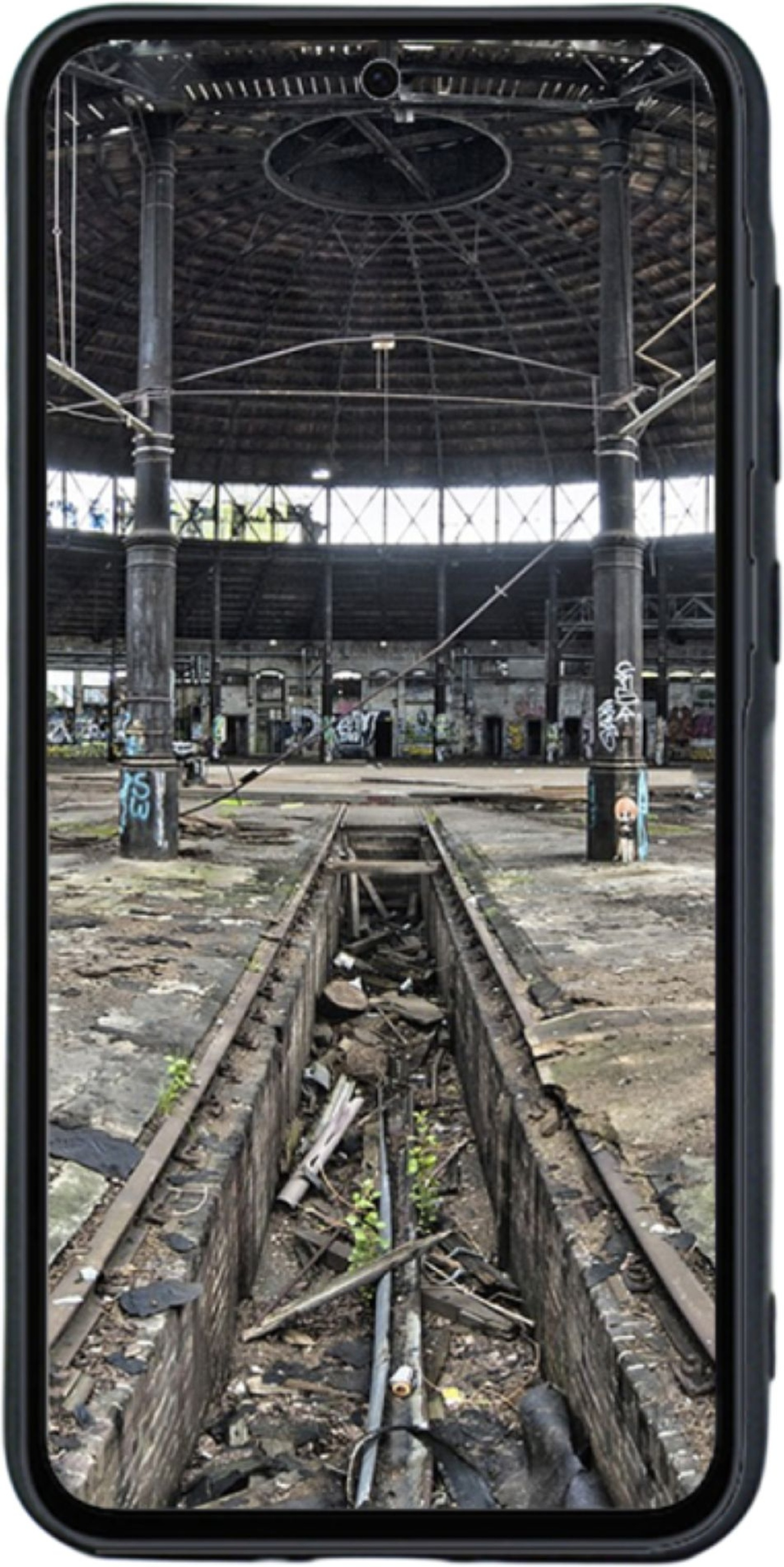 Un écran de smartphone affichant l'intérieur d'une ancienne gare, avec des voies.