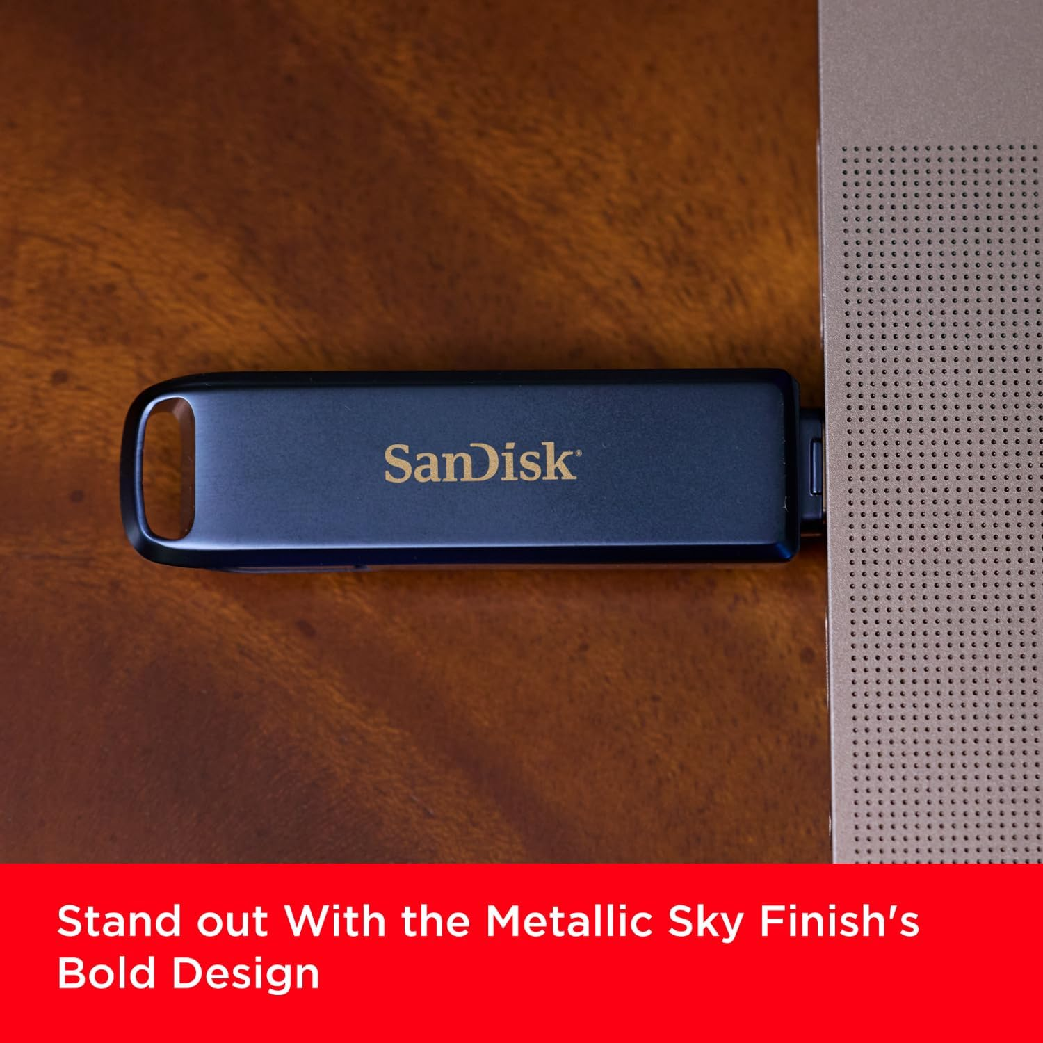 Une clé USB est insérée dans un ordinateur portable. La clé est noire avec le logo Sandisk. Le fond est en bois.