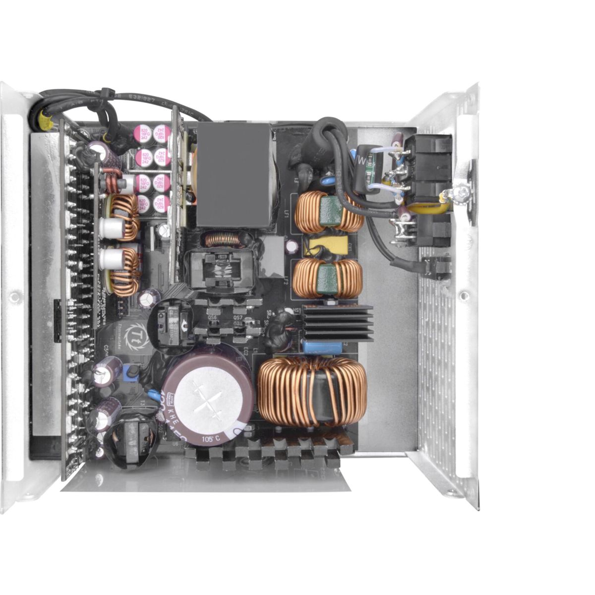 Otwarta płytka drukowana z różnymi komponentami elektronicznymi. Widoczne cewki miedziane i kondensatory.
