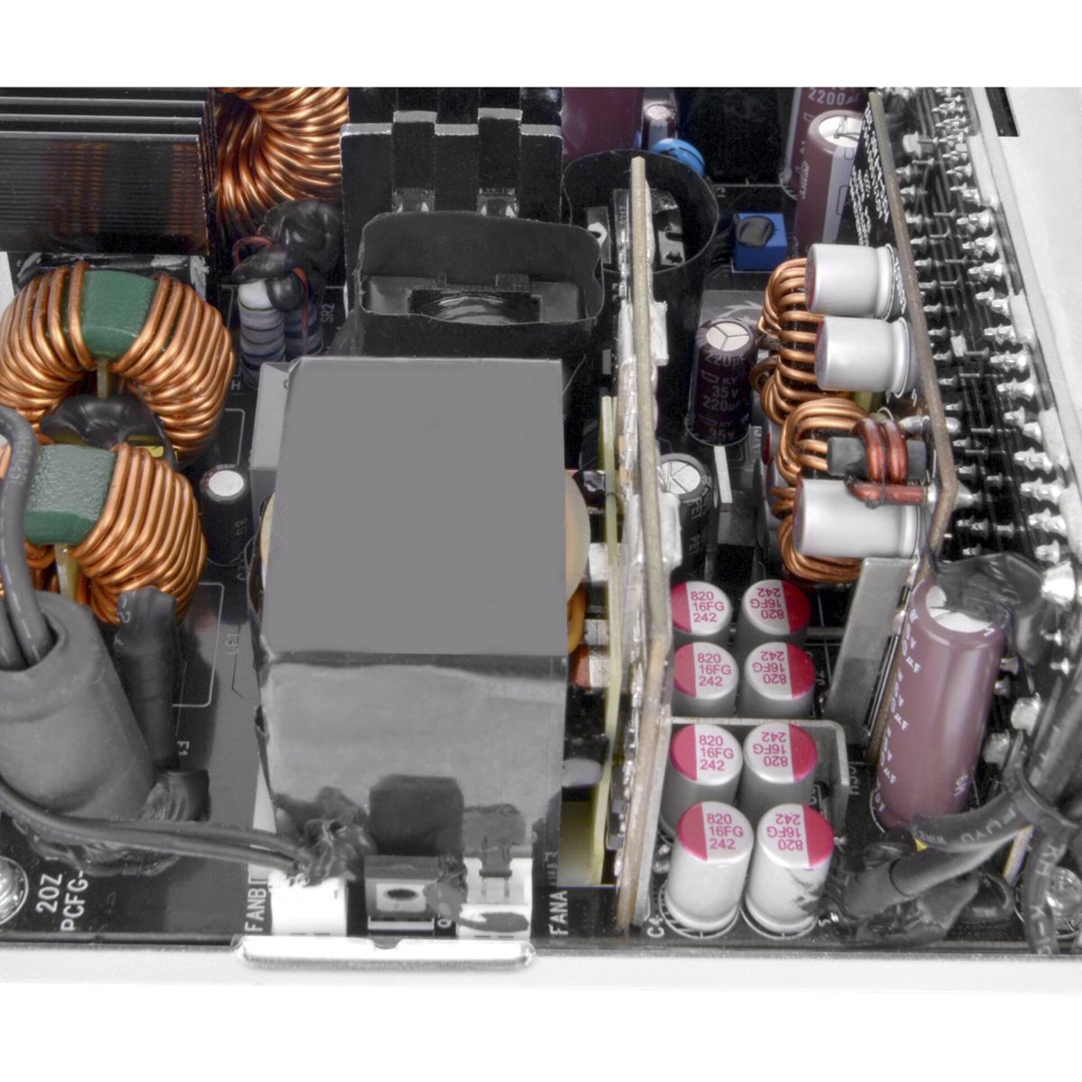 Zbliżenie otwartej płytki drukowanej z wieloma elementami elektronicznymi. Cewki miedziane, kondensatory i inne części.