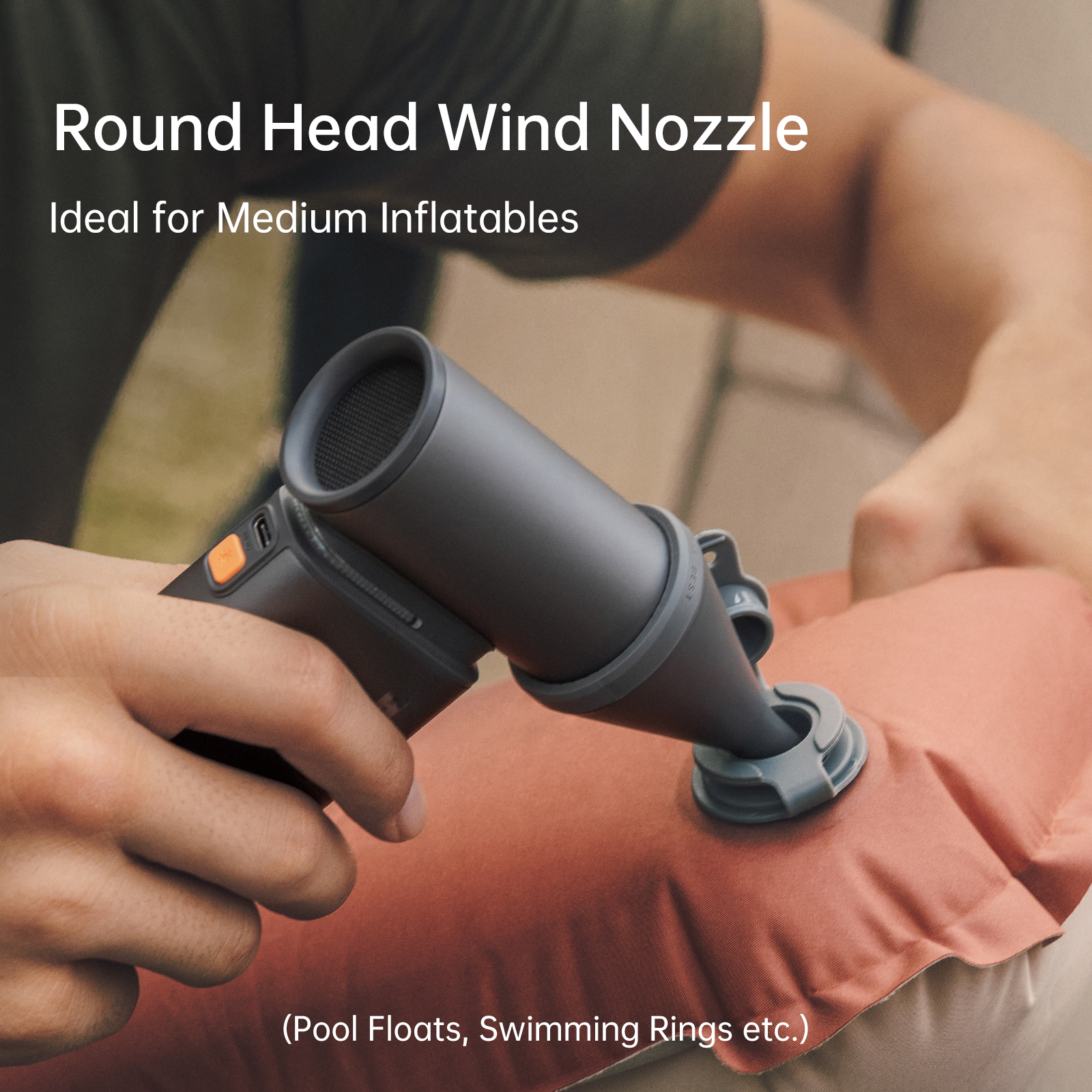 Una persona usa una boquilla de viento de cabeza redonda para inflar un inflable rojo. La boquilla es gris oscuro.