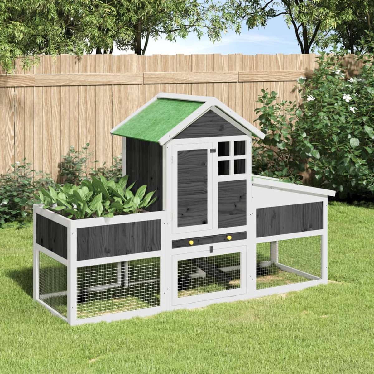 Ein Hühnerstall in einem Garten mit grünem Dach. Grünes Gras, Pflanzen und ein Zaun.