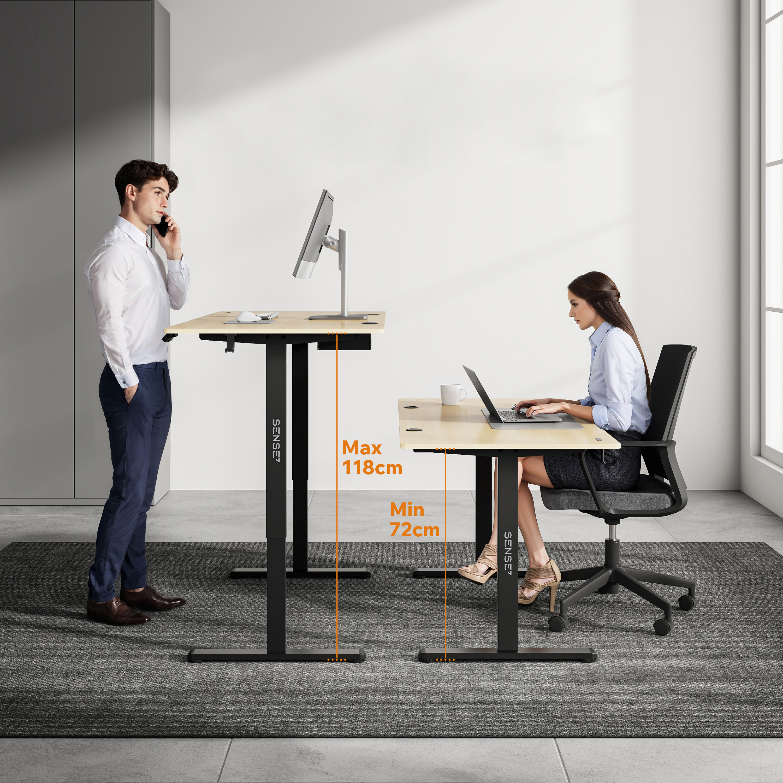 Twee personen aan verstelbare bureaus. Eén staat, telefonerend, de ander zit en werkt op een laptop.