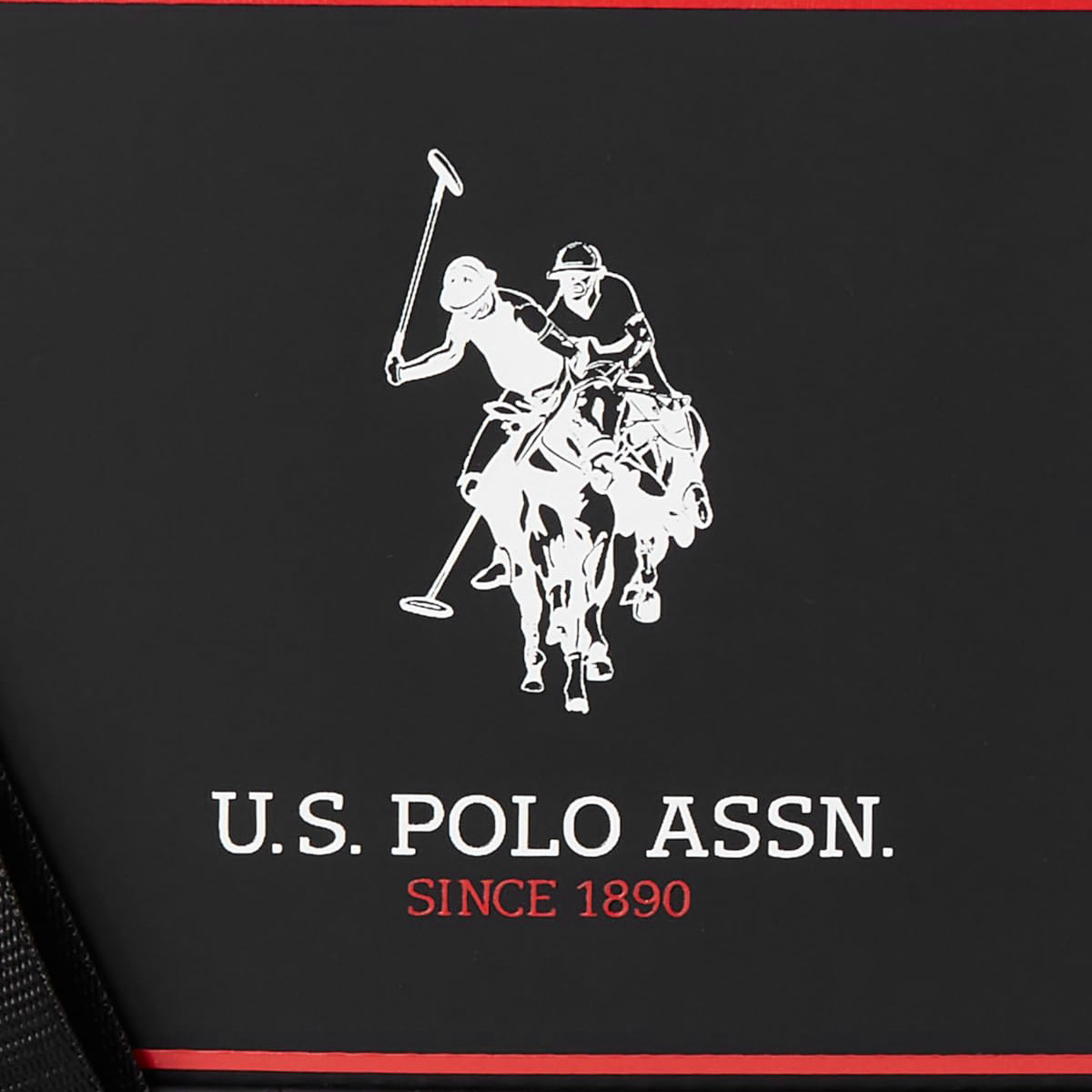 Nahaufnahme des US Polo Assn. Logos auf einer schwarzen Tasche. Es zeigt einen Polospieler auf einem Pferd und Text darunter.
