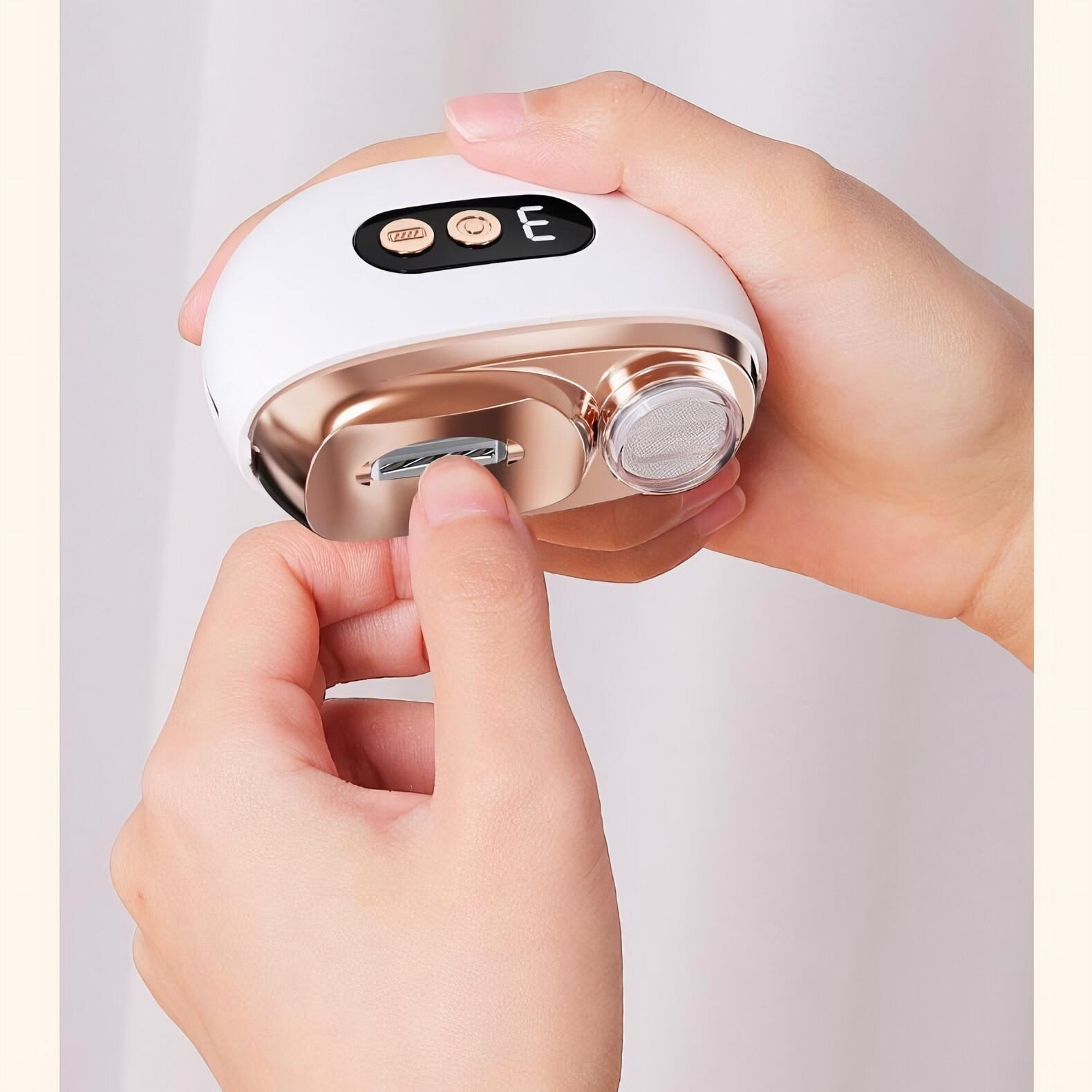 Die Hand einer Person schiebt eine weiße und goldene elektrische Nagelfeile auf einem weißen Hintergrund auf.