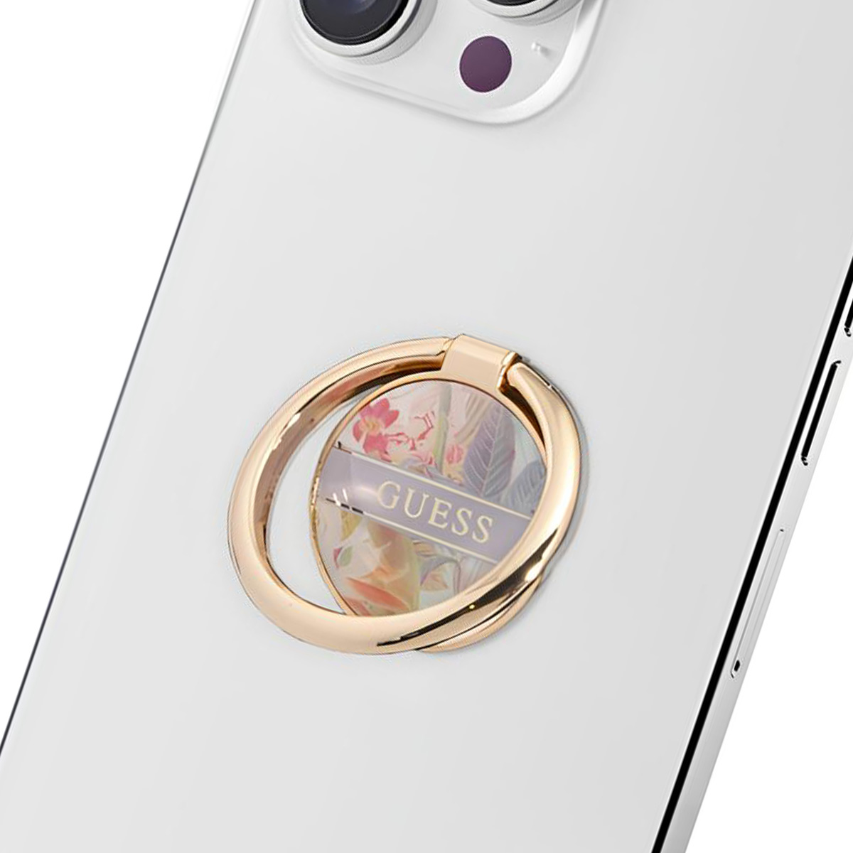 Une bague de téléphone dorée avec un motif floral est fixée au dos d'un téléphone blanc. Le mot 'GUESS' est visible.