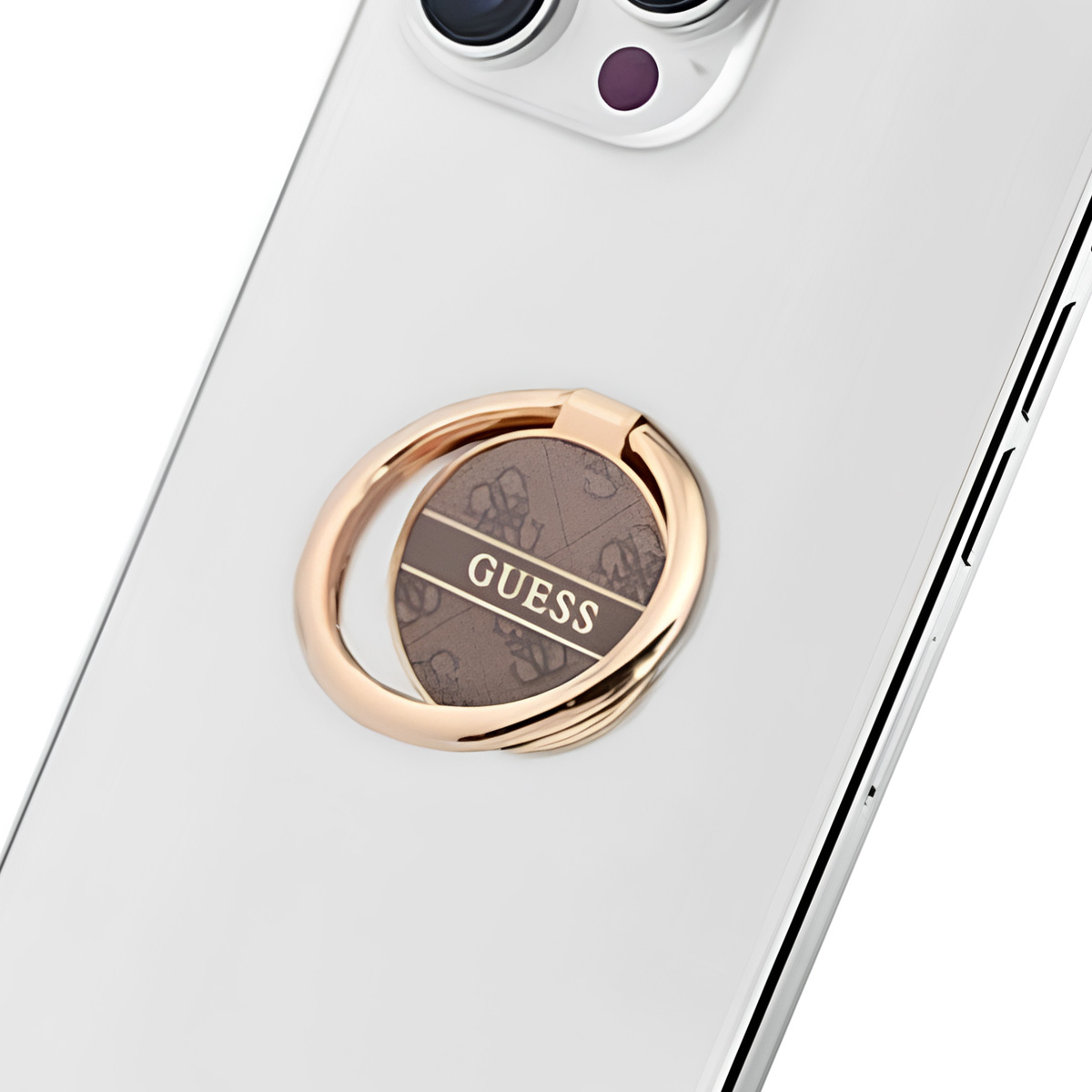 Un téléphone avec un dos argenté, un support de bague doré avec le logo Guess.