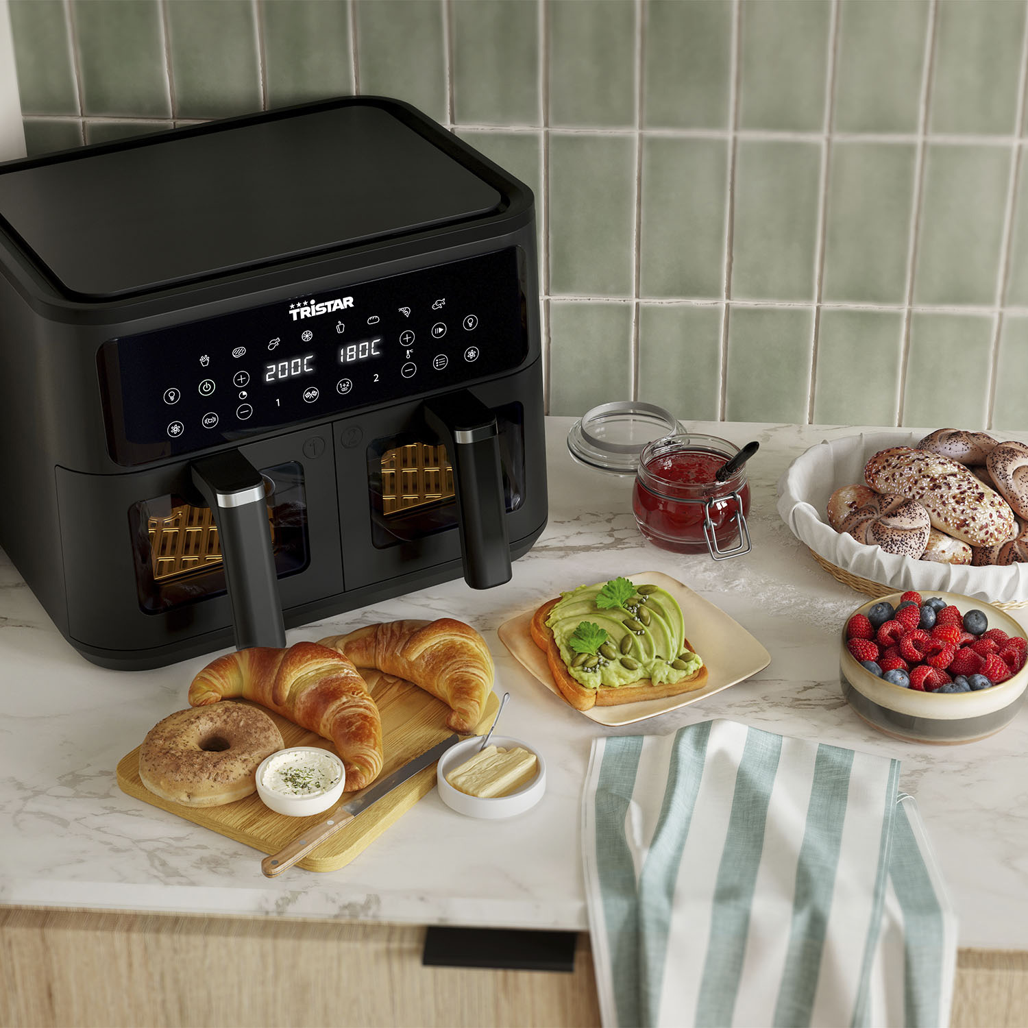 Black air fryer with food, croissants, and toast on a marble countertop.